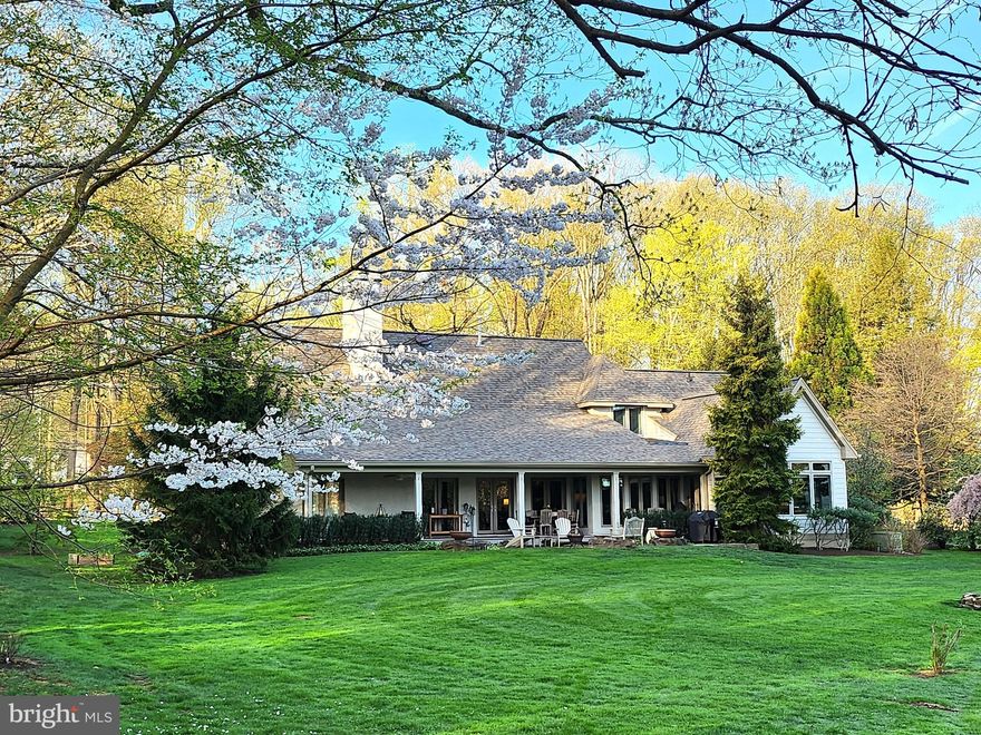 Extraordinary house designed by renowned Doylestown architect, Ralph Fey, is the epitome of a comfortable and gracious lifestyle. The setting, house, landscaping, pond, location, serenity, and beauty are unparalleled. The detailed architectural features and amenities, inside and outside, make this a very special home. Every season enters this house with views. Built to include the outdoors as part of the ambiance of this home, large windows and front and rear porches emphasize relaxing and entertaining. The exciting floor plan includes a first floor primary bedroom suite with a luxurious bathroom, enormous walk-in closet, door to the rear porch, and one of the soaring 18’ ceilings. The heart of this home is the great room and chef’s kitchen with beams that were milled from Poplar trees on the property. Note the recessed built-ins, two elegant chandeliers, foyer with skylight letting in natural light. A raised hearth natural gas fireplace is the focal point of this open floor plan that includes a formal dining room.  A chef’s kitchen has custom glass-paned cherry cabinets, specially fitted drawers, quartz countertops, Wolf 6-burner range, Sub-Zero refrigerator, and an island with seating and deep sink. The sitting or casual dining area overlooks the pond. This floor also has a second bedroom/den/office with a full bathroom that is also accessed from the hall. The windowed sunroom is a quiet spot in which to relax, unwind, and enjoy the view. A natural gas freestanding fireplace is surrounded by exquisite mill work, and within this room is a cleverly converted closet that now is a compact office. Behind the kitchen there is a large pantry with floor to ceiling wood shelves, coat closet, laundry room, doors to the 3-car garage and to the huge basement. Walk up the curved staircase to the second floor and a wall of custom made photograph shelves. One side is a bedroom with walk-in closet, and dual access full bathroom with individual vanity and sink and shared toilet and bath/shower. The other side is a bedroom or multi-use room that is fabulous space with a 16’ ceiling, closet, storage window seat. Whatever your needs, this beautiful home has space for it. The basement is an open canvas with 10’ ceilings and walls are already fitted with Superior Wall System panels with insulation. Fabulous space, great possibilities. Generac whole house generator, water conditioning system, custom Plantation shutters on every window, custom closets throughout, upgrades, classic style and taste, highest quality products and materials, innovative touches, make this both a country and sophisticated home that is an idyllic retreat. The extensive landscaping is a natural and integral part of this extraordinary property. Nature surrounds you; trees shelter you; shrubs and flowers delight you, and there is even a creek that goes under a wood bridge and flows into the pond at one end and spills over the dam at the other end. Close to New Hope, Doylestown, and the best of Bucks County dining, shopping, recreation, and entertainment, the location is convenient for commuting to Philadelphia, Princeton, and NYC. Welcome home to your own private oasis.