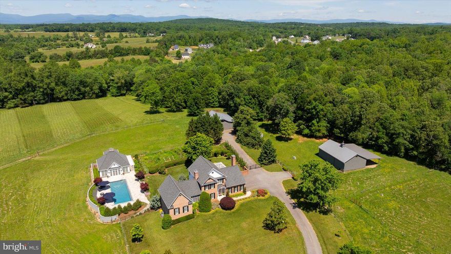 Resort-Style Living Meets Refined Country Luxury on 13 Private Acres!  Welcome to 10042 Cedar Spring Lane in Culpeper—a serene sanctuary where elegant architecture, beautifully maintained acreage, and exceptional outdoor living spaces come together in perfect harmony. This extraordinary estate is more than a residence—it’s a lifestyle defined by serenity, beauty, and boundless possibility. Custom built and thoughtfully enhanced throughout the years, the main brick Colonial residence offers over 3,500 square feet of elegant living space with four bedrooms, 4.5 baths, and timeless architectural detailing. Tucked away at the end of a tranquil gravel drive, the estate enjoys total privacy with curated landscaping, gently rolling pastures, and distant Blue Ridge Mountain views that set the scene in every season. - THE GROUNDS & EQUESTRIAN FACILITIES - Designed for animal and horse lovers alike, 12 acres of the property are dedicated to fenced, lush pastures, thoughtfully divided into eight paddocks with 10 heated automatic waterers. There are two barns—the larger a 40x60-foot facility complete with four stalls (one is double – perfect for a broodmare), tack and feed room, storage space, three overhangs, and even a chicken coop. The second barn is ideal for hay storage and features an oversized covered overhang. A small creek meanders through the land, and the setting is alive with local wildlife, from deer and foxes to wild turkeys. - THE GUEST AND POOL HOUSE RETREAT - The recently constructed (2018) guest/pool house is a showstopper. The exterior with crisp white siding sets a sophisticated tone, and inside, soaring coffered ceilings, a striking six-foot stone fireplace, and an open-concept kitchen and dining space evoke upscale hospitality. A full bath and sauna are located on the main level, while a separate outdoor staircase leads to an upstairs bonus room with half bath and panoramic views. The custom, heated pool includes eight jets, an automatic cover, and a travertine surround, all bordered by lush gardens and a stone privacy wall that make it  perfect for family gatherings and entertainment. - THE MAIN RESIDENCE - Elegant and warm, the home is richly appointed with oak hardwood floors, plantation shutters, and three gas fireplaces on the main level. The main living areas flow effortlessly—highlighted by a formal living room, cozy family room, and light-filled sitting room with French doors and floor-to-ceiling windows. The main-level primary suite offers a walk-in closet, full laundry, and an ensuite with double vanities and custom tilework. The gourmet kitchen—renovated with style and class—features Viking appliances, granite countertops, and cherry cabinetry, flowing into a sunny breakfast area and adjacent glass-enclosed sunroom with access to an expansive brick patio and pergola. - UPPER & LOWER LEVELS - Upstairs are three additional bedrooms, including a luxurious second primary suite with dual walk-in closets and a large ensuite bath. A third full bath completes the upper level. The finished lower level is an entertainer’s dream with a spacious media/family room, full bath, kitchenette, laundry area, large storage room, and a pool table area (pool table negotiable). Mechanical updates include a new water heater (2025) and a newer HVAC unit (2022). There are also two private wells on the property. -  LOCATION - Despite its private, rural ambiance, this estate is just 3 miles from downtown Culpeper, with easy access to Routes 15, 29, and 3. Orange is just 20 minutes away, and Fredericksburg is less than an hour’s drive. 10042 Cedar Spring Lane is not just a home—it's an unparalleled opportunity to own a one-of-a-kind equestrian estate with resort-level amenities in one of Virginia’s most picturesque settings!