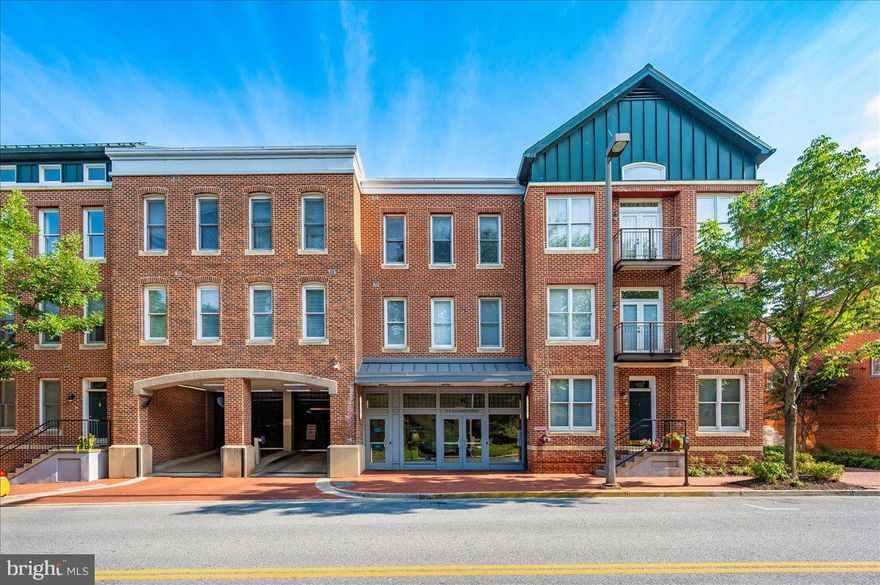 Welcome to the penthouse of the Maxwell Building — a top-floor, 2-bedroom, 2-bathroom condo offering unmatched luxury, prime downtown location, and some of the most spectacular views in Frederick. This rare rental opportunity combines elegant finishes, abundant natural light, and premium building amenities to create a living experience you’ll be hard-pressed to find anywhere else. From the moment you step inside, you’re greeted by a welcoming foyer — a versatile space perfect for a small desk, reading nook, or a stylish bench to kick off your shoes after a stroll along Carroll Creek. The home opens into an airy, open-concept living and dining area, where vaulted ceilings amplify the sense of space and light. A cozy fireplace adds warmth and character, making this the ideal place to unwind or entertain. Two private balconies offer completely different experiences: one overlooks historic Carroll Creek, where you can listen to the soothing sounds of fountains and watch the gentle flow of water; the other faces the charming Maxwell Plaza courtyard, perfect for sipping your morning coffee. The updated kitchen is a chef’s delight, featuring brand-new quartz countertops, a gas range for precision cooking, and abundant cabinetry for all your storage needs. Hardwood floors run through the main living areas, while both bedrooms have been upgraded with brand-new carpeting for ultimate comfort. The spacious bedrooms are filled with natural light, and the two full bathrooms are beautifully appointed with tasteful finishes. This secure, elevator-access building ensures peace of mind and convenience, with controlled entry and well-maintained common areas. Your lease includes two reserved garage parking spaces and access to a private indoor, lockable storage unit — a rare luxury in the heart of the city. Residents also enjoy the on-site fitness center, so staying active is easy without ever leaving home. Perfectly located just steps from Downtown Frederick’s finest dining, boutique shopping, art galleries, and entertainment, this home offers the very best of city living with a touch of tranquility.