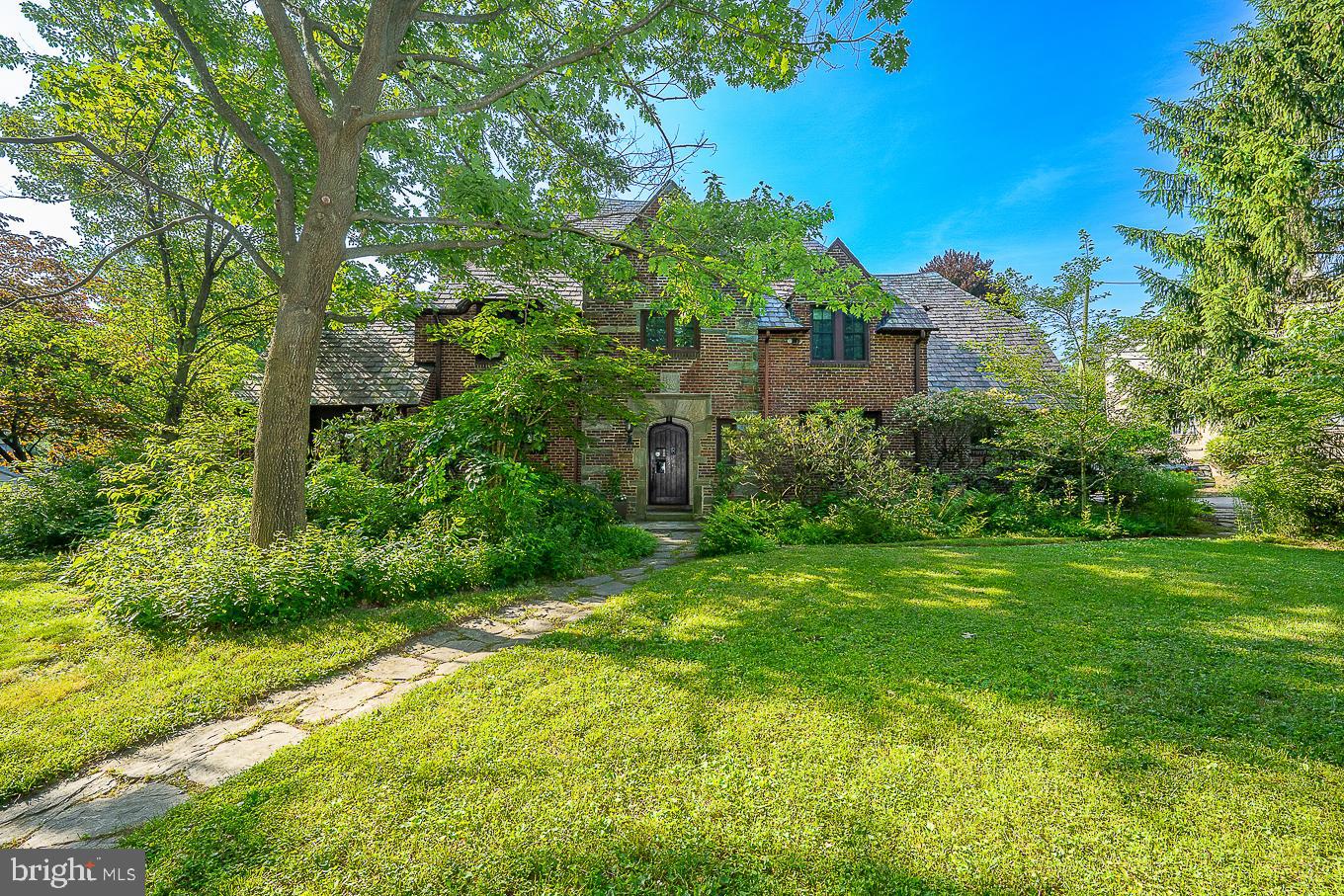 Situated on a picturesque, tree-lined street in Wynnewood, sits this beautiful brick 4 Bedroom/3.5 Bath home with over 3,200 sq/ft on .62 acres of private grounds surrounded by native plantings. Old world charm combined with modern amenities makes this the perfect place to call HOME. As you walk through the front door, you will immediately be greeted by the curved banister, archway into the Dining Room and hardwood flooring. Step into the Living Room with hardwood flooring and be swept back into time where the gorgeous fireplace with brick surround and an intricately designed wood mantel, window seat and built-ins awaits. From the formal Dining Room, pass through the Butler’s pantry to the sun-lit, renovated eat -in Kitchen. The Kitchen boasts a granite counter tops, center island with round table and seating, all stainless steel appliances including a Subzero refrigerator, 5 burner cooktop, microwave drawer, double oven, 2 pantry cabinets and recessed lighting. A Den, Powder Room, 3 season Sun Porch with ceiling fan (perfect time of year to enjoy) complete the main level. On the 2nd Floor, you’ll find the Primary Suite, 3 additional Bedrooms (1 en suite) and 2 offices. The Primary Bedroom suite offers dressing room with 2 closets, which could be combined with the dressing room to make 1 large closet, and updated Primary Bath with frameless glass shower, granite flooring and pedestal sink. Bed #2 and Office #1 features a jack and jill Bathroom. The 3rd Bedroom has a nice closet and hardwood flooring. In a separate wing on the 2nd floor, you’ll find Bedroom #4 with en suite updated Bathroom, Office #2 and stairs to the amazing 3rd floor finished, air-conditioned, versatile Attic. Laundry and an abundance of storage in the Basement. The magnificent, professionally-designed natural appearing landscape with extensive native plantings, stone patio, 2-tiered spacious wood deck, offer utmost privacy, beauty and serenity. This special Tudor home offers exquisite detailing inside and out and should not be missed! ***Please be aware that Den and Powder Room are missing in the virtual tour