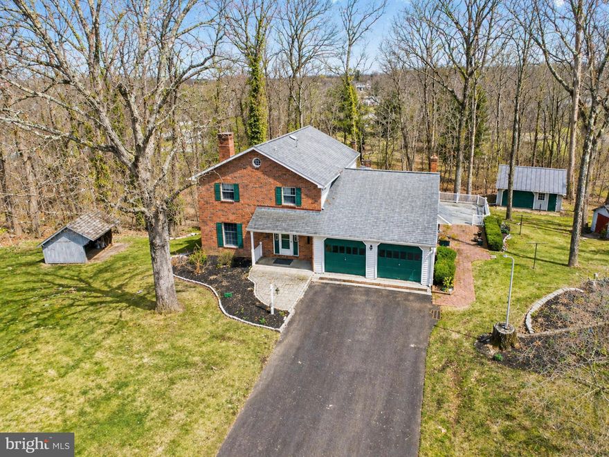 Nestled on a picturesque, tree-lined 2.08-acre lot in the highly desirable Souderton Area School District, this beautifully maintained 3-bedroom, 2.5-bath home offers a rare blend of privacy, character, and refined living. Step inside to a warm and inviting interior where thoughtful design and quality craftsmanship are evident throughout. The heart of the home is the spacious kitchen and dining area, featuring an abundance of solid wood cabinetry, generous counter space, a center island, tile backsplash, and a peninsula with seating—perfect for everyday living and entertaining. The sun-filled dining area is enhanced by crown molding, a large picture window, and an elegant chandelier, creating a bright and welcoming atmosphere. The expansive living room exudes timeless charm, highlighted by a classic brick fireplace with a detailed wood mantel, rich trim work, crown molding, and oversized windows that fill the space with natural light. A stunning sunroom serves as a true showpiece, offering walls of windows, wood-paneled walls, an exposed beam ceiling, skylights, and a ceiling fan. With direct access to the rear deck, this space is ideal for relaxing or entertaining year-round. The main level is completed by a convenient laundry area and powder room. Upstairs, the spacious primary suite provides a peaceful retreat with ample room and double closets. The beautifully updated ensuite bath offers a spa-like feel, featuring a stylish vanity, sleek fixtures, and a large walk-in tile shower. Two additional generously sized bedrooms share a remodeled hall bath with granite countertops and updated finishes. Adding even more value is the expansive attic space, offering excellent potential to be finished for a 4th bedroom or additional living space—perfect for a home office, bonus room, or guest area—or simply used for abundant storage. The walk-out finished basement provides exceptional versatility, featuring a large recreation area with a cozy stove and stone accent wall, along with a second kitchen—ideal for entertaining, extended stays, or in-law potential. Direct outdoor access enhances the functionality, while unfinished areas allow for additional storage or future expansion. Outside, the property is equally impressive. A long private drive leads to a timeless brick façade, complemented by mature landscaping and an elevated setting with stone retaining walls and serene wooded views. Enjoy outdoor living at its finest with a spacious rear deck and charming patio—perfect for hosting or unwinding in a peaceful setting. In addition to the oversized attached 2-car garage, the property features a 15 x 20 detached garage/outbuilding ideal for a workshop or hobbies, plus a 9 x 10 storage shed for added convenience. This exceptional property offers the perfect balance of comfort, functionality, and privacy—an ideal place to call home.