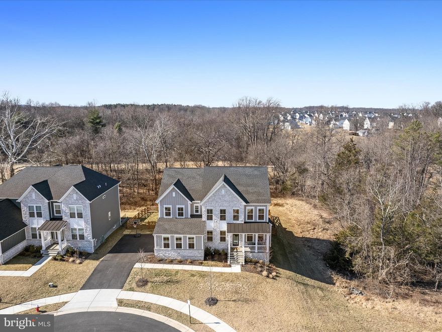 Welcome Home to this stunning DRB Emory II Model in Loudoun County!
Nestled in the sought-after Hartland community in Aldie, VA. This extraordinary home offers 6 bedrooms and 5.5 bathrooms across 5,131 finished sq ft. Situated on a .24-acre cul-de-sac lot backing to serene trees and a walking path.  Privacy and sunset views await!  At less than 2 years old, this property is almost new and features many upgrades including all builder optional windows and extra recessed lighting.
This floorplan is designed for both elegant living and entertaining. Step inside from the slate front porch to discover a bright and spacious main level featuring LVP flooring throughout, crown molding and coffered ceilings. There is a formal dining room, a home office with glass doors for privacy, and a drop zone and coat closets for organization.  The 2.5 car side-load garage is designed to be spacious and versatile, providing ample room not just for two cars but also for extra storage. The additional vertical space can be a game-changer for organizing things like shelves, cabinets, or even hanging storage for tools and equipment.
The gourmet kitchen is a chef’s dream with quartz countertops and backsplash, stainless steel appliances, soft-close cabinet doors, walk-in pantry, and a pot filler.  Pull up a seat at the large island or sit at the table in the eat-in dining area overlooking the private backyard. The kitchen seamlessly flows into a spacious family room perfect for gatherings.  You can cozy up to the stone fireplace while reading a book or watching TV. Just off the kitchen, there is a main-level bedroom and full bath providing flexibility for guests or multi-generational living.
Upstairs, you will find a spacious, light filled loft that can serve as a second living area or hang out space for the kids.  Also on this level, there are 3 bedrooms and the primary suite.  The primary suite is a true retreat with double entry doors, vaulted ceilings, a sitting area, and two walk-in closets. The en-suite bath features a frameless shower, large vanity with dual sinks, and separate water closet.  Two of the additional bedrooms are adjoined by a buddy bathroom with dual sinks.  A third bedroom, full bathroom, and laundry room with utility sink round out this level.  
This finished basement is a standout feature, offering a wealth of additional living space perfect for various needs. The wet bar area is ideal for entertaining, while the bonus room, complete with a rustic barn door, can easily serve as a home gym or media room (already wired for a future projector). There is  an additional bedroom with an egress window, large closets, and a full bathroom providing more comfortable living space. Step outside through the walk-up to the backyard, perfect for outdoor activities or relaxation.
Outside, the home features a stunning large composite deck with stairs leading down to a stamped concrete patio, creating the ideal outdoor entertaining space. The fully fenced backyard offers privacy and security providing an enclosed space for pets and kids to play. 
Top-rated Loudoun County Public Schools make this home even more appealing for families. Home is wired for CAT6/7 throughout.  With all the builder upgrades and additional custom enhancements, this home is truly a one-of-a-kind gem!
Community amenities include: community pool, tennis & basketball courts, walking trails, and a gym.  This home is just minutes from shopping, dining, Dulles airport, and major commuter routes, while offering an idyllic retreat to come home to.
Don’t miss your chance to own this meticulously upgraded, move-in-ready home! Contact us today to schedule your private tour.