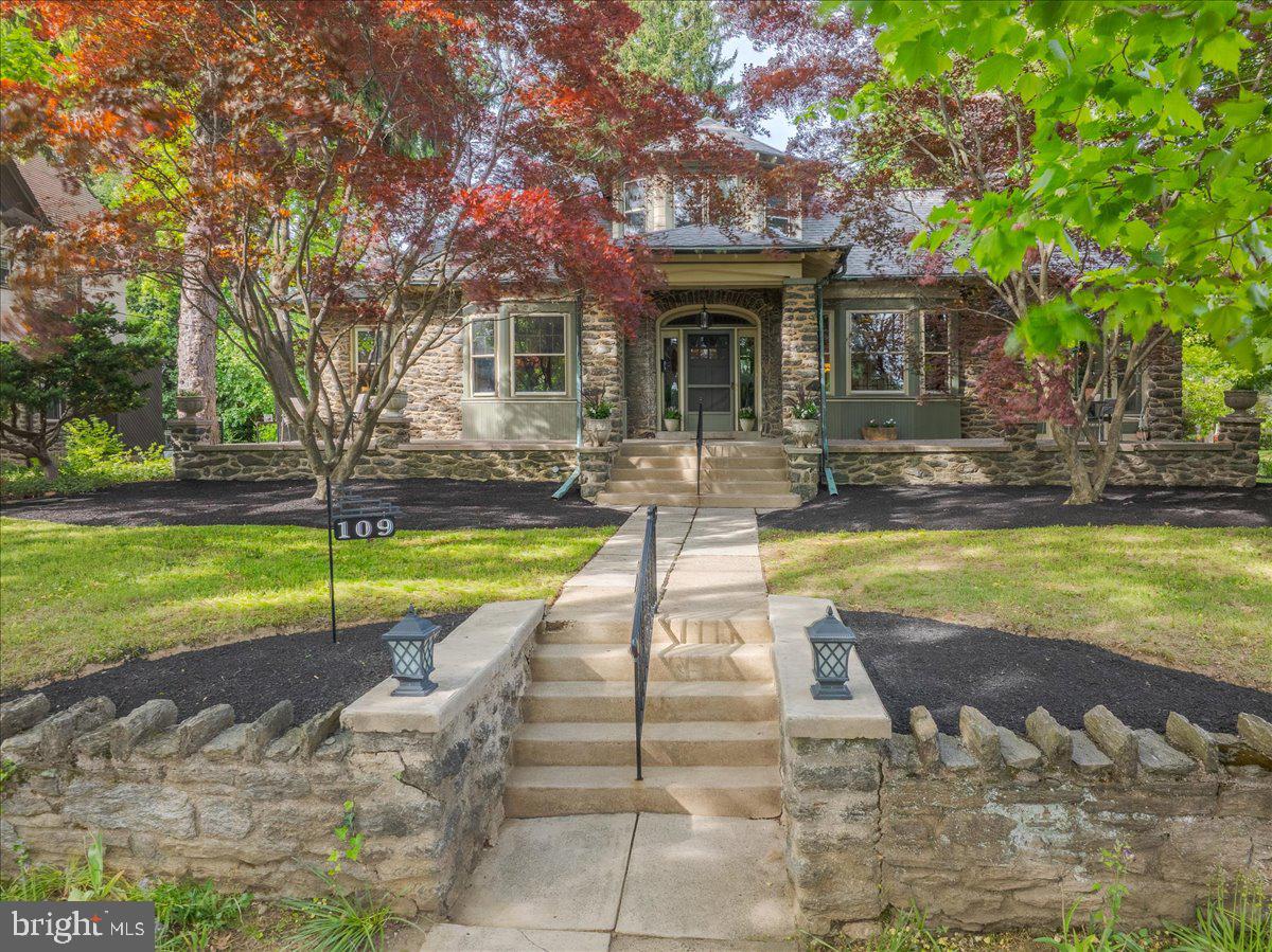 Some houses just have soul. You feel it the moment you step onto the wide front porch—like this place has stories to tell, but still plenty of room for yours. Built in 1917, 109 Surrey Road is a large Craftsman house, full of timeless details that give it both warmth and presence. With over 4300 square feet of living space, it offers the character of a historic home with the scale and flexibility today’s lifestyle demands. Wide hallways connect the main spaces, original wood trim wraps each doorway, Mercer tile frames the fireplaces, and rich flat-panel wainscoting and coffered ceilings elevate the space without ever feeling too formal. The rooms are grand but grounded—like the 23 x 15.5-foot living room, perfect for quiet reading, hosting a friend, or entertaining a crowd. Pocket doors connect you to a comfortable family room ideal for movie nights, and just beyond that, a sun-soaked office with tall windows creates a peaceful spot to work or hide away. Dinner parties feel right at home in the elegant dining room—nearly 20 feet long, with French doors and two built-in china cabinets ready to showcase your glassware. Off the dining room, there’s an enclosed front porch that faces east—flooded with morning light and perfect for coffee, Wordle, and petting your pup before starting the day. The kitchen is spacious and bright, with Quartz countertops, stainless steel appliances, and a charming breakfast nook for casual meals. Just around the corner, a hidden laundry room keeps things practical, while a surprise bar room sets the stage for your next cocktail night. Don’t miss the unexpectedly spacious powder room—complete with eye-catching original tile work that adds a little wow factor where you least expect it. This home offers the convenience of first-floor living with two generously sized bedrooms and a full bathroom all on the main level. Upstairs, the large, sun-filled primary suite is a true retreat. The bedroom alone is approximately 25 x 23 feet, with two large closets and a bonus room that can be anything you need—home gym, office, nursery, or walk-in closet. The en-suite bathroom adds a modern touch with a shower stall, tub, updated vanity, and new flooring. A second upstairs bedroom has its own full bath as well. The unfinished basement offers plenty of storage or room to expand in the future. Outside, the backyard feels like a blank canvas—ready for soccer games, summer dinners, or a hammock under the mature trees. The detached garage adds flexibility, and being on a corner lot gives the whole property a sense of breathing room. When it’s time to step out, you’re about half a mile from the Melrose Park train station, with direct service to Center City and the airport. Parks, coffee shops, and local restaurants are all nearby. It’s walkable and connected, yet scenic and quiet enough to recognize you’ve found someplace special. This isn’t just a house—it’s a rarely found, spacious bungalow with presence, heart, and a front porch that’s been waiting for you.
