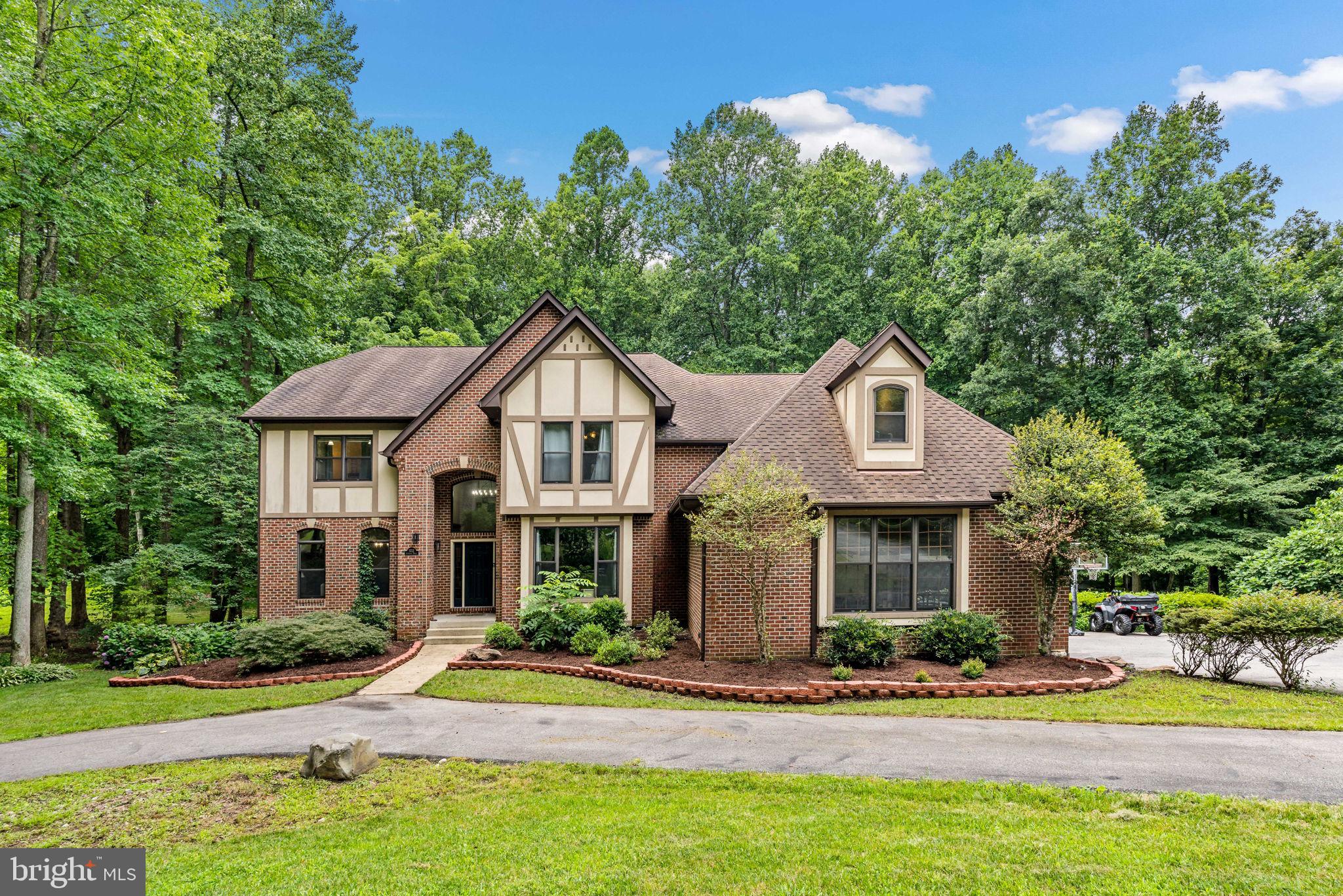 No HOA. RECENT IMPROVEMENTS IN PAST 4 YEARS TOTAL $229,320. See Document section for full details list of improvements.
An enchanted forest, tucked away down a private drive on 2 acres. There’s plenty of room for the whole family to have their own space. This charming French Tudor estate is a class built with modern upgrades. New LVP hardwood floors less than 2 years old; all appliances, main HV/AC, and water purification system under 5 years old, and the second level HV/AC less than a year old.
The main level includes two separate living areas, a dining room, walk-in pantry, a huge laundry room that doubles as a mudroom with ample storage, a spacious office with wall-to-wall built-in bookshelves, and located at the center of the home is a custom-built one-of-a-kind chef’s kitchen. This culinary dream was completely renovated with upgrades less than a year ago including custom built cabinets with soft close features, a generous island with room to gather, entertain, and create memories. The refrigerator, dishwasher, and microwave are less than a year old. The kitchen extends into an eat-in area opening up to the second living space with soaring two-story ceilings and gallery windows to enjoy the view of your private fenced in backyard. Going up the back staircase is a custom-built accent wall that houses a built-in workspace in the open loft area.
Upstairs you will find five spacious bedrooms, one with its own private bathroom with a walk-in shower and updated fixtures and vanity. The main bathroom on the second level has been updated with new fixtures and vanities as well. The Primary suite is a relaxing retreat with a sliding door to a private balcony overlooking the backyard. You are met with two separate closets in the hallway down to the connected en-suite. This relaxing en-suite has plenty of room for couples to get ready for the day without getting in each other’s way, a private water closet, separate vanities, a walk-in shower, and an extra-large garden tub.
The basement is a unique versatile space that doubles as a completely private basement apartment. The sixth bedroom in the basement has it’s own entrance, bathroom (with ne fixtures and vanity), and a full kitchen with appliances less than five years old. The rest of the basement can be used as a theatre room, rec- room, or game room. No need to worry gym space as there is a dedicated gym complete with mirrors and a full built-in sauna. The home has an attached three-car and located in the backyard is a detached double garage workshop. The location is a commuters dream a short drive to Andrews Airforce Base, Annapolis and the Naval Academy, Chesapeake Beach, and still conveniently distanced to Washington D.C. only half an hour away. This is a property you will truly have to see to believe.