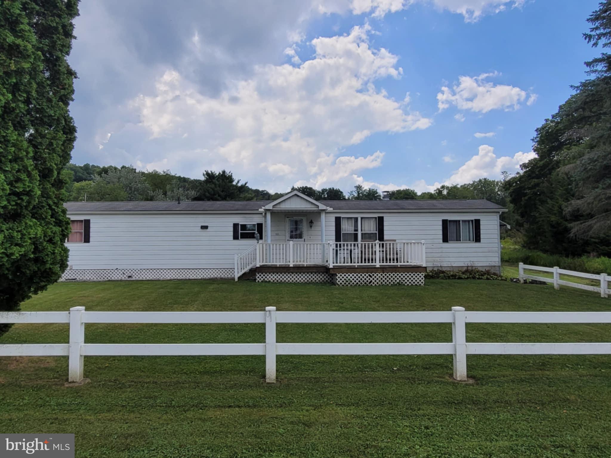 This well-cared-for home sits on a beautiful , level .57-acre lot and features a 2-car detached garage, pavilion, and barn—ideal for storage, hobbies, or entertaining. The front yard is lined with white decorative fencing and a partially covered front porch, offering a welcoming space to enjoy both sun and shade. Inside, you’ll love the thoughtful layout, featuring a spacious living room with a cozy fireplace, and a bright eat-in kitchen with ample cabinetry, pantry, and closet space. One side of the home includes the primary bedroom, full bath, and laundry area; the other offers a second bedroom with its own half bath—perfect for guests or a home office. The back entryway features warm wood walls and additional storage closets. Great storage throughout, plus a brand-new natural gas furnace for peace of mind. Contents remaining in the home are available for purchase.