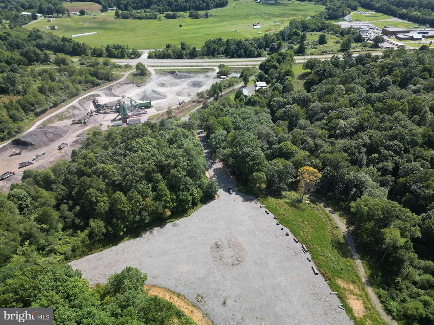 Explore the potential of this versatile industrial outdoor storage site in Nicholas County. Located at 405 Checks Road in Summersville, WV, this approximately 5-acre graveled lot—part of a larger 20-acre parcel—has been thoughtfully prepared for heavy-duty use. With a 1-foot gravel base installed over geotextile fabric and a built-in stormwater management system, the groundwork is already in place for a wide range of uses.
This property is ideal for outdoor storage, equipment laydown, fleet parking, material storage, or contractor operations, offering the flexibility to adapt to your specific needs. Whether you're storing heavy equipment, staging materials, or expanding your business footprint, the possibilities here are wide open.
The site features a gated entrance designed to accommodate two trucks side-by-side, allowing for smooth and efficient access. A truck scale and small scout house are already in place, adding functionality for logistics and day-to-day operations.
Positioned with convenient access to key roadways, the property is just minutes from WV Route 39, connecting Summersville to Richwood, and US Route 19, providing a direct route to Fayetteville, Beckley, and surrounding areas.
Surrounded by a mix of open land and wooded scenery, the setting offers both privacy and flexibility—while still being close enough to town for everyday conveniences.
Whether you're looking for a dedicated storage yard, a place to grow your operations, or a strategic investment opportunity, this property offers the space, infrastructure, and accessibility to bring your vision to life.