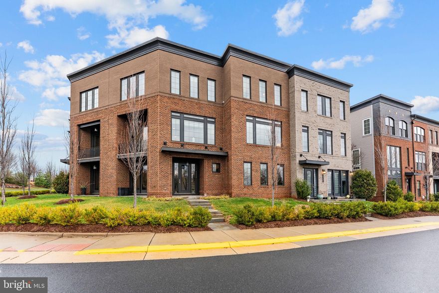 Welcome to 23132 Brooksbank Square, a beautifully designed Belgrave floorplan by Miller & Smith, built in 2018 and offering over 3,100 square feet of stylish, flexible living in the heart of Brambleton’s sought-after Garden District.

With architecture reminiscent of a classic New York brownstone, this three-level townhome blends timeless charm with modern functionality. Inside, you’ll find two spacious primary suites, an additional bedroom or office, three full bathrooms, and two half bathrooms—thoughtfully designed to accommodate today’s dynamic lifestyles.

The main level features a bright, open-concept layout with seamless flow between the living, dining, and kitchen spaces—ideal for both everyday living and entertaining. Just off the kitchen, step out onto your private deck, perfect for morning coffee or summer barbecues.

Upstairs, the home truly shines with two primary suites on the third level, each offering generous space and en-suite baths—creating a rare and versatile retreat ideal for guests, multi-generational living, or dual home offices.

The lower level provides additional living space perfect for a recreation room, home gym, or office, while the two-car garage and low-maintenance lifestyle make daily living effortless. The HOA handles lawn care, and Verizon internet is included, offering both convenience and value.

Located in Brambleton’s Garden District, you’ll enjoy beautifully maintained trails with lush landscaping and greenery right outside your door. The community offers over 18 miles of paved trails that thoughtfully pass under roads for uninterrupted access, connecting neighborhoods, parks, and the vibrant Brambleton Town Center.

At the Town Center, you’ll find shops, restaurants, Harris Teeter, and a beloved Sunday farmers market. Residents also enjoy access to five outdoor pools, community centers available for private events, sports courts including basketball, pickleball, and tennis, as well as stocked ponds for recreational fishing.

This is more than a home—it’s a lifestyle rooted in connection, convenience, and elevated everyday living.