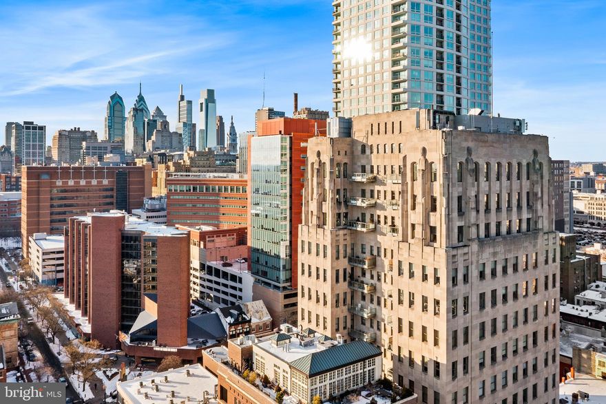 Ideally positioned just steps from Washington Square, this corner residence at The Ayer pairs Art Deco architecture with modern refinement in one of the city’s most distinguished full-service buildings. The Ayer’s dramatic lobby and facade remain a true design statement - a rare blend of historic character and contemporary luxury. Inside #6SW, nearly 12-foot ceilings and expansive windows on three exposures capture exceptional western and southern light, filling the home with warmth throughout the day and delivering striking sunsets. A gracious entryway features a coat closet and a well-appointed powder room. The open living and dining spaces feel both expansive and inviting, anchored by a sleek Bulthaup kitchen designed for elevated everyday living and entertaining. Wrapped by 8 oversized windows, the living, dining, and kitchen area feels open and airy, with city views unfolding as you cook, dine, and unwind. The serene primary suite offers generous scale, city views, and a walk-in closet. The custom stone bathroom features a double vanity and large shower tucked behind frosted glass, complete with a rain shower head. The bathroom also boasts integrated storage, including a built-in laundry hamper and safe.  A thoughtfully separated guest suite includes its own full bathroom, closet, and laundry. White oak floors run throughout the apartment. A private balcony extends the living space outdoors, creating a quiet urban retreat above the city. Residents of The Ayer enjoy concierge and valet parking (limitations apply to oversized vehicles), fitness center access, and use of a chauffeur-driven BMW 7 Series. Just blocks from Thomas Jefferson University Hospital, Pennsylvania Hospital, acclaimed restaurants, coffee shops, and local favorites like Talula's Garden and Daily, along with the green space of Washington Square, this is sophisticated city living defined by light, design, and service.