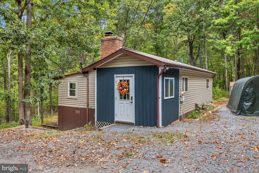 Discover peace and privacy in this inviting two bedroom, one bath mountain cabin nestled on three beautiful wooded acres - just one property shy of the National Forest.  Step inside to find a spacious kitchen with ample counter space and cabinets, perfect for home cooked meals and entertaining. The dining room features a cozy pellet stove, creating a warm and welcoming gathering space.  An addition provides a large living room ideal for relaxing, plus a bonus room that can serve as a home office or den,  The convenient mudroom includes laundry with a washer and dryer combo.  Two access points lead to the crawlspace, offering plenty of extra storage.  Enjoy the outdoors on the expansive patio area - great for hosting gatherings - or explore the wooded surroundings.  The property also includes two sheds for added storage and a large, level driveway with ample parking.  Experience mountain living at its finest - peaceful, private, and just minutes from outdoor adventure!