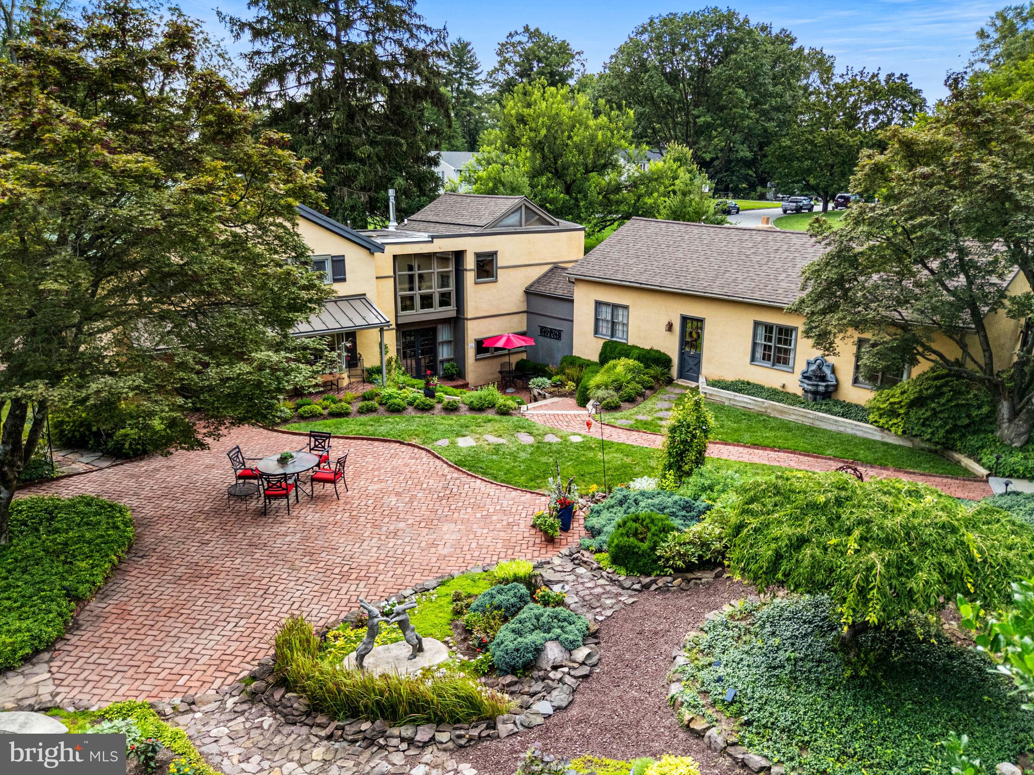 Historic Carriage House with Timeless Charm in Schuylkill Township
Welcome to the original carriage house of the historic Supplee Dairy Farm—offered for the first time in over 50 years. Built circa 1800, this distinctive home blends early-American character with thoughtful modern additions (1982 and 2002), offering 4,916 square feet, 4 bedrooms, and 2.5 baths—all nestled in a private, landscaped setting in sought-after Schuylkill Township.
A Pennsylvania bluestone walkway lined with mature trees leads to a charming red brick path that opens into the home’s inviting courtyard. Surrounded by lush perennial gardens and manicured hedges, the courtyard features multiple seating areas, ideal for relaxing or entertaining. A covered front porch welcomes guests, while a lower-level double-door entrance opens to a dramatic two-story foyer, showcasing exposed stone walls and generous natural light.
Inside, the updated kitchen offers granite countertops, stainless steel appliances, custom cabinetry, and a built-in coffee bar with glass-front accents and under-cabinet lighting. The adjoining dining room includes original built-ins, space to comfortably seat eight, and a floor-to-ceiling picture window that frames the beautiful view of the private courtyard and surrounding gardens.
The historic charm continues in the original sitting room, where stone walls, hand-hewn wooden beams, and a wood-burning fireplace create a cozy atmosphere. At the back of the home, a vaulted-ceiling bonus room with propane fireplace, custom shelving, and expansive windows offers beautiful garden views and direct access to a side patio lined with mature boxwoods and the private side yard.
Upstairs, the primary suite sits privately in its own wing with a spacious walk-in closet and an ensuite bath featuring a walk-in shower. The other side of the house features three additional bedrooms and a full bath providing comfortable accommodations for family or guests.
An attached heated studio—formerly a floral design workshop—is now an art studio and workshop with water access, offering great potential for a home office, in-law suite, or creative space. The original milk house remains on the property, perfect for storing gardening tools or future repurposing.
This is a rare opportunity to own a home that combines rich history, unique architectural features, and modern comfort—all within a welcoming neighborhood known for its top-rated schools, scenic surroundings, and strong sense of community. It’s a home designed for living, gathering, and growing.