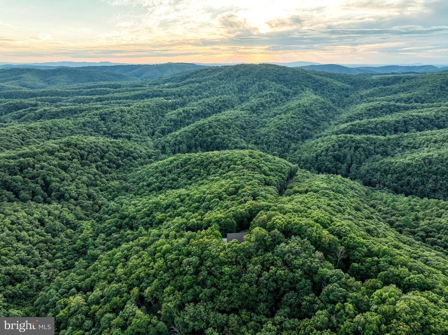 Tucked away in the mountains of Greenbrier County, West Virginia, this 383+/- acre secluded retreat is a recreational paradise offering unparalleled privacy and breathtaking beauty. With million-dollar views stretching as far as the eye can see, this property is an outdoor enthusiast’s dream, blending rugged wilderness with endless opportunities for adventure and relaxation.

The rolling topography is laced with miles of roads and trails, perfect for exploring by truck, ATV, UTV, horseback, or on foot. Whether you enjoy hiking through the forest, riding along ridgelines, or simply taking in the views, the land is designed to be both accessible and inviting. A diverse hardwood forest, including white and red oaks, provides an exceptional habitat for wildlife and includes stands of marketable timber.
The property is teeming with wildlife, making it a haven for hunters and nature lovers alike. Whitetail deer, turkey, black bear, and small game roam the ridges and hollows, while songbirds and other woodland creatures add to the richness of the environment. With such abundant wildlife and varied terrain, it is a property that can be enjoyed in every season.

Ideally situated just 13.5 miles from The Greenbrier Resort, 9.5 miles from Moncove Lake, and within close proximity to the George Washington and Jefferson National Forest as well as the Greenbrier State Forest, the property is surrounded by some of the region’s most treasured outdoor and cultural attractions. From world-class golf and fine dining at The Greenbrier to boating, fishing, and camping at nearby lakes and forests, there is no shortage of activities within easy reach, while still maintaining a sense of unmatched seclusion.

Perched in the heart of the property is a 3,100+ square foot mountain home that perfectly complements the setting. Designed to showcase its surroundings, the home features cathedral ceilings and floor-to-ceiling windows that frame panoramic views of the Allegheny Mountains. A spacious wraparound porch provides the ideal spot to watch the sunrise with your morning coffee or enjoy cool mountain evenings with friends and family. The home itself has solid bones and a new roof, offering an excellent foundation for someone with vision. While it is in need of significant TLC and updates, it has all the potential to be transformed into a stunning mountain retreat or family estate.

This property represents more than just acreage—it is a private sanctuary where adventure, beauty, and opportunity converge. Whether you’re looking for a personal hunting retreat, a family getaway, or a legacy property to be passed down for generations, this Greenbrier County mountain escape is a rare find. With its expansive views, rich natural resources, proximity to renowned destinations, and the potential to create a one-of-a-kind residence, it truly stands as a remarkable offering in the heart of West Virginia’s Allegheny Mountains.