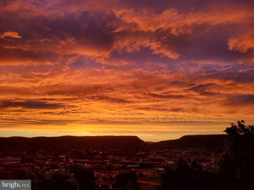 City and Mountain views in a park like setting on a dead end street = privacy Unique 4 bedroom, bonus room, 3.5 full baths on 1.82 acre lot (79,279 sq ft lot).Great view of the Cumberland Narrows & valley with year round sunsets and moonset city lights view. All remodeled over the last 20 years: drywall, electric, plumbing, gas heating, new central A/C -Heat Pump installed 5/24/24, modern kitchen, roof (12 years old), tall ceilings & tall thermopane windows throughout natural light galore, 1st floor bathroom with whirlpool tub and walk-in shower, terraced patio, court yard. New hot water heater.  Private parking-dead end street. Including a  joining 1+ ACRE buildable lot (1.82 acres total). All located in the heart of Cumberland, in a park like setting. Separate finished interior 12 x 16 building (once was Glory House Chapel). Easy access to all Cumberland has to offer: walking distance to grocery, post office, Amtrak, schools, museums, and of course C & O bike trail. Plus near-by Deep Creek Lake. SOON: Wills Mountain State park at Lover's Leap. We've had 13 years of fun here. Beautiful Crescent Moonset on 6/11/2024. Sold as-is. If you want a house with a view this is a must see , call to schedule a showing & directions