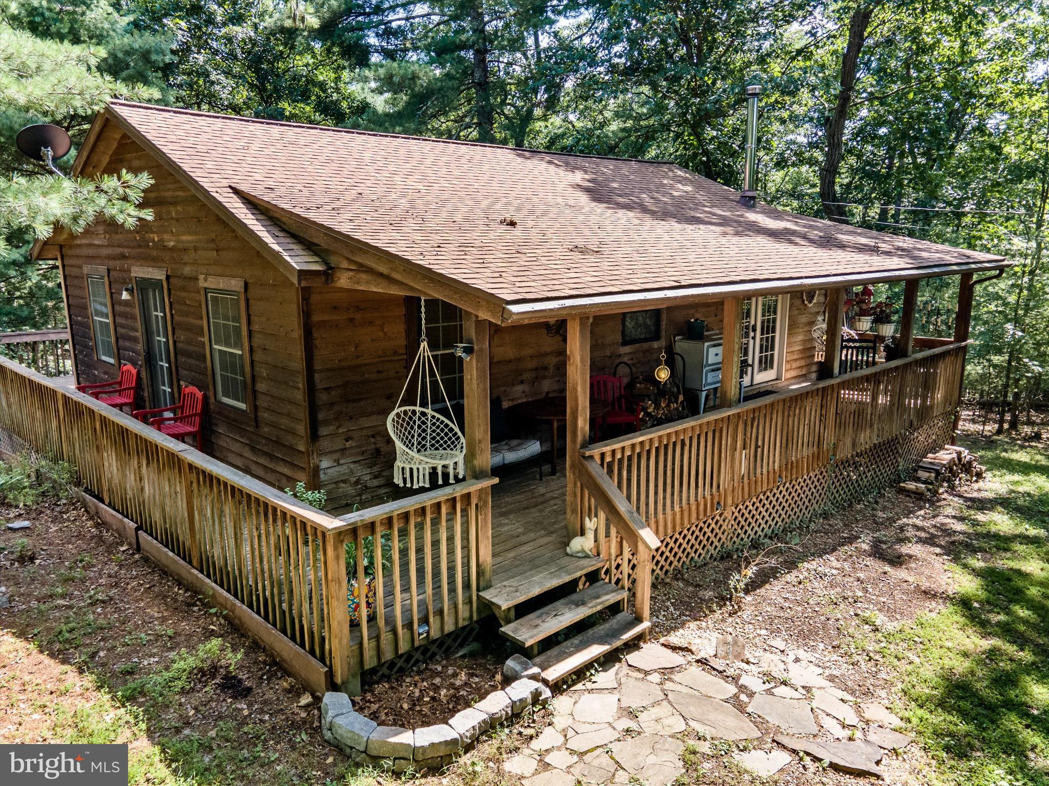 Escape the everyday—your woodland retreat awaits. Tucked away on 5 peaceful acres in Gerrardstown, WV, this charming home offers the perfect balance of seclusion and convenience, just 20 minutes from Winchester, VA, and Inwood, WV shopping, dining, and commuter routes.
Enjoy the sights and sounds of nature from the wrap-around deck, or take a stroll among the mature trees. The home is full of character, featuring parquet wood floors throughout, a cozy wood-burning fireplace, and plenty of unique touches. The kitchen has green cabinetry, open shelving, a granite countertops, and a farmhouse cast iron sink overlooking the backyard. The hallway bathroom has been fully renovated with a dreamy soaker tub for the ultimate relaxation.
Major updates have already been taken care of—including the HVAC, roof, hot water heater, and well pressure tank—so you can move right in without worry. High-speed internet from Starlink makes it easy to work from home, stream, or stay connected.
The oversized detached garage provides plenty of space for parking, a workshop, or extra storage. Plus, the low-maintenance cedar siding means more time enjoying your retreat and less time on upkeep. The outdoor furniture, trampoline, hammock, and even a tree nest net—perfect for climbing up to relax among the trees can convey!
Whether you’re looking for a weekend escape or a full-time sanctuary, 142 Cressen Dr. delivers privacy, charm, and modern comfort—all wrapped up in a woodland setting.