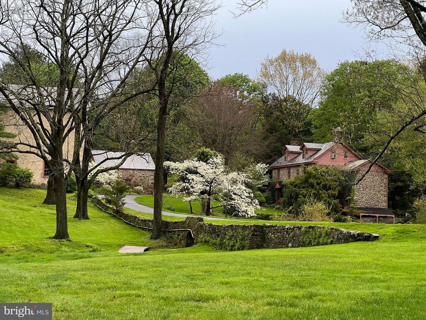 First time offered in nearly 45 years, Esteburne Farm is a quintessential Bucks County estate set on 39 preserved acres along a quiet country road in Solebury Township, New Hope, Pennsylvania. Tucked far from the road in a postcard setting, the property is a remarkable collection of historic stone structures surrounded by rolling pastures, mature trees, and serene countryside. The estate includes a stone main house, stone carriage house, stone garage, stone bank barn, corncrib, equipment shed, and both indoor and outdoor riding arenas, creating an exceptional equestrian compound with timeless character. Built in 1760, the main residence offers four bedrooms, three stone fireplaces, hardwood floors throughout, and beautiful views from every window. Historic details such as high-beamed ceilings, a graceful staircase, and original architectural elements reflect the home’s rich heritage. A large stone patio overlooks the pastoral landscape, while a seasonal stream crosses beneath a charming stone bridge along the drive, adding to the property’s storybook setting. A two-bedroom carriage house, privately situated a comfortable distance from the main residence, provides ideal guest accommodations or a caretaker’s residence. The all-stone bank barn is equally impressive, featuring chestnut floors, 30-foot soaring ceilings, six horse stalls, and a heated woodworking shop. With its dramatic scale and historic character, the barn offers extraordinary potential for a future residence, studio, or event space.