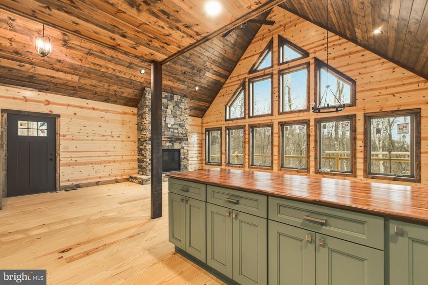 Brand New Log Style Chalet at Deep Creek Lake! Newly completed in 2026, this beautifully crafted mountain home blends elevated design with thoughtful efficiency. The main level showcases an open layout with dramatic vaulted ceilings, walls of windows, and rich wood finishes that create a bright yet grounded living space. A floor-to-ceiling stone fireplace serves as the centerpiece, adding both character and comfort. The kitchen is designed with both style and function in mind, featuring stainless steel appliances, custom cabinetry, and a generous island that anchors the space. Overlooking the main living area, the loft provides a versatile extension—ideal for a secondary lounge, workspace, or guest retreat. Bedrooms and baths are finished with a cohesive, high-quality feel throughout. Constructed with energy-efficient elements and durable materials, the home is built for year-round comfort and lasting performance. Step outside to a spacious deck set within a private wooded setting, offering a natural backdrop for relaxing or entertaining. The home sits within Nature's Run, a new mountain community tucked into the original woods and natural terrain of Wisp Mountain. The development places attainable cost homes within an ecosystem of 8.5 acres of forest, rock formations, and stream. Hiking trails run throughout the property and connect to large green space areas contiguous to Nature's Run. Ideally located at the center of the Deep Creek vacation area, Nature's Run is just a few minutes from McHenry and all of its amenities and marinas for Deep Creek Lake. It is very close to the Wisp Resort lodge and upper ski access, Lodestone golf club house, and within minutes of all of the nature areas associated with the Youghiogheny River. This property presents a compelling opportunity for those seeking a primary residence, second home, or high-end investment with lasting value.