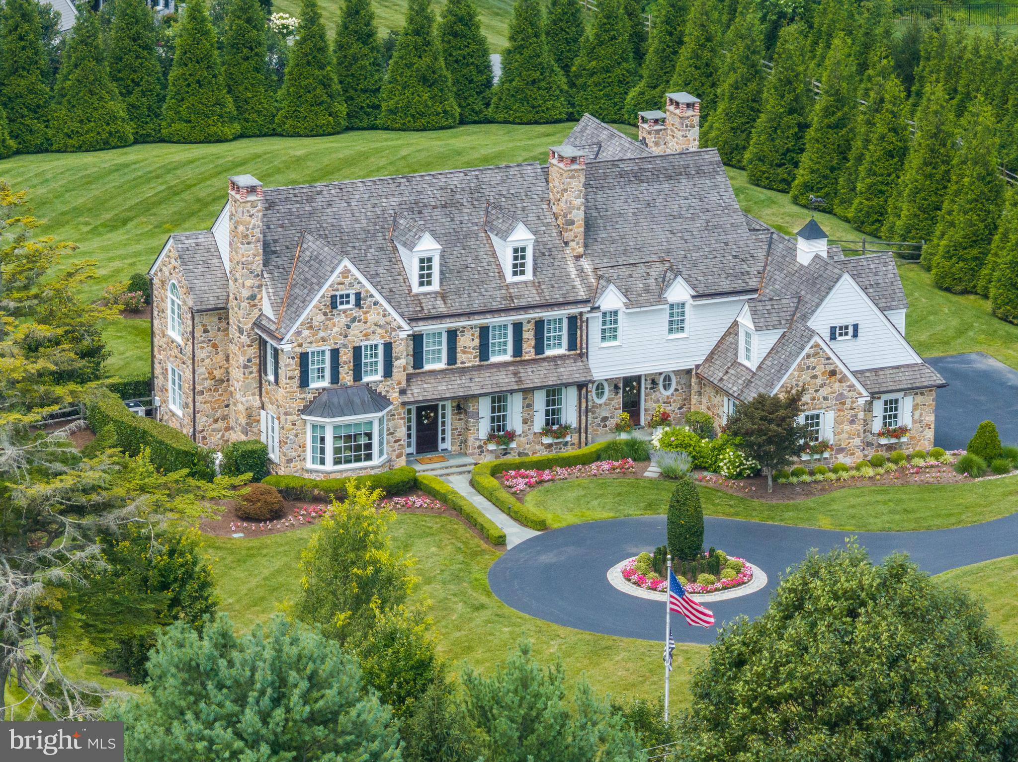 Welcome to 2211 White Horse Rd Berwyn- an absolutely stunning, 8 year young, completely custom farmhouse that sits on a breathtaking 1.9 acre lot in top rated Tredyffrin-Easttown school district. When building this 5 bedroom, 4.4 bathroom “dream” home, no expense was spared and no detail was overlooked. The goal when building this home was for the outside to look like an historic Radnor Hunt farmhouse while the interior would have the updates and luxuries of a new construction home. Seamlessly blending 6 inch non-cut Chester County fieldstone, premium cedar shake shingles, copper gutters and flashing, and louver and solid shutters, this home looks like it was designed by R. Brognard Okie himself.
The interior with a formal, yet open floor plan offers 9 foot ceiling height on all 3 levels; 5 inch hardwood oak flooring throughout the first and second levels; 5 masonry fireplaces - 3 wood burning and 2 gas; custom inset cabinetry, vanities and built-ins courtesy of Kountry Kraft in Devon; built-in closet systems and walk-in pantry designed by California Closets; and detailed trim, millwork, moldings, and decorative ceilings throughout. Formal spaces include a dining room with wood burning fp; a living room with gas fp, and an office with built-in bookcases and a private powder room. The heart of the home is the gourmet kitchen with 9.5 foot island, Sub-Zero and Wolf appliances, Calacatta marble counters, marble mosaic backsplash, white, beaded inset cabinets and an attached breakfast room with vaulted, beamed ceiling. Connected to the kitchen is a butler’s pantry with beaded, inset cabinetry, mahogany top, stamped copper sink, and a floor to ceiling paneled Sub-Zero wine/beverage fridge. From here, step down to the cozy and bright family room with coffered ceiling, floor to ceiling stone fp (wood burning) flanked by built-in bookcases, and French doors to the exterior. The first level is completed with an additional powder room and a mudroom with built-ins that exits to the oversized, heated 3 car garage.
The second level offers a luxurious primary suite with a vaulted, decorative ceiling with chandelier lighting; French doors to a balcony that overlooks the rear yard; dual walk-in closets; and a spectacular en-suite marble bathroom with dual vanities, soaking tub and spa-inspired shower. There are 4 other spacious bedrooms - all with walk-in closets. Two bedrooms share a full bathroom with shower/jetted tub combo and a vanity with attached “glam” area and the other two bedrooms share a bathroom with a stall shower and vanity that has an attached built-in bench for storage. Above the garage is a huge bonus space with a built-in entertainment wall with two televisions for gaming or for viewing - this area could be used as a 6th bedroom. The second level is completed with a laundry room with plenty of cabinet and counter space to make doing the wash a breeze. The finished lower level with a side walk-out entrance/exit has an open floor plan with a gas fp; a pub style wet bar with grey, inset cabinetry, soapstone top, dishwasher, and Sub-Zero wine fridge, beverage fridge and ice maker; a professional style gym with custom made barn doors, mirrored walls, and rubber flooring; a powder room; a full bathroom off of the gym; and a 2nd office.
The fully fenced, flat rear yard is not to be missed with an expansive blue stone flagstone patio that surrounds a salt-water pool/hot tub and extends into the pool house. The pool house is a replica of the main house and offers a vaulted, beamed ceiling; a wood burning fp; powder room with built-in cubbies; stainless steel cabinetry; 2 refrigerators; a built-in Wolf grill; and a wet bar area with island seating. Walkable to Episcopal Academy and close to many other top academies, minutes to downtown Wayne, Malvern and Ellis Preserve, and easy access to the Philadelphia Airport, Paoli train station and major roadways for an easy commute. Call today for more information!