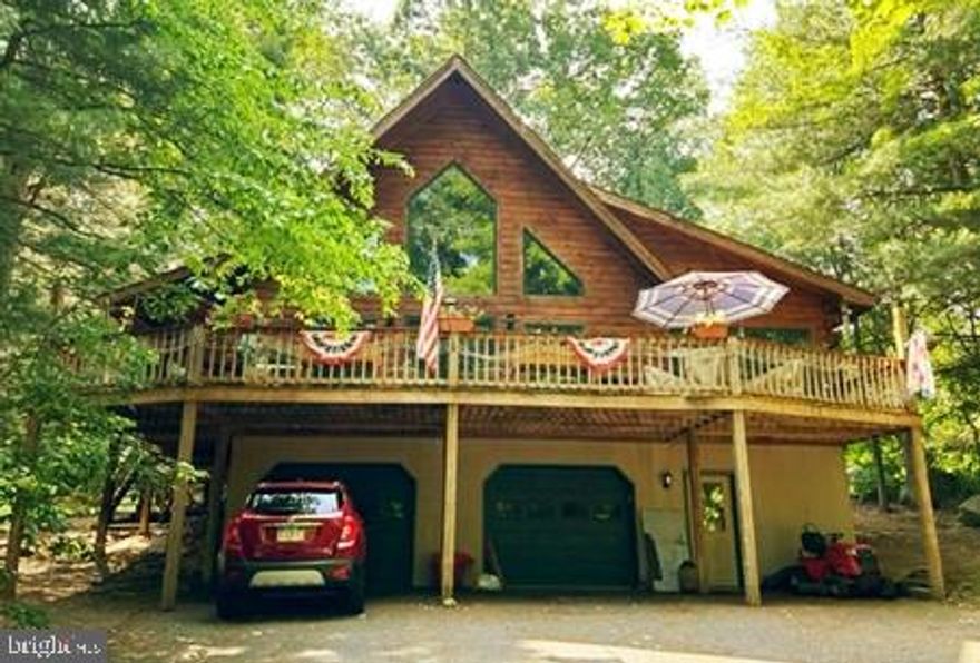 More Photos on the way!  
Watching wildlife while sipping morning coffee or evening wine tastes so good from wrap around deck of this unique home!
This unique home offers rustic privacy all wrapped up in an open floor-plan.  18 Ft Cathedra Cilings in the LR area are graced with floor to ceiling windows with that feeling of being one with nature.  Exposed beams, actual real wood floors and corner fireplace finish off the Living Room experience. 
Additionally with a 1st Floor Bedroom complete with private bath and WI closet, a quaint dining area, wrap-around custom, hickory wood kitchen loaded with cabinets and storage, this home could easily be a One-Level living experience.   1st Floor also offers mud-room with laundry, powder room.  
Up the actual wooden beam stairs, guests or family will find 2 additional bedrooms, full bath and balcony overlooking the rear of the land.
Additional features include Wrap-Around Deck, 2 Car Garage, Interior Storage Area, Interior Heated Workshop, Central Air, Efficient Heating System and New Roof in 2020.