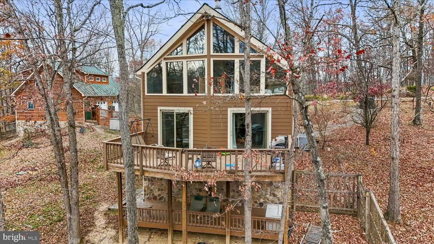 Welcome to Crossings View! This beautiful home, nestled on top of the Cacapon Mountain is more than just a cabin! Topping the ridge you are greeted with this 3 bedroom home and large 2 car garage with additional living space and bar/studio! Inside the home take in the natural light, the views, vaulted ceilings and open concept! The open concept kitchen, living room and dining room are complimented by the beautiful hardwood floors, an eat-at kitchen island with range, a main level bedroom and bath, the floor to ceiling windows in the living room overlooking the deck and yard, and the separate dining and breakfast area! Upstairs is the primary suite with a lofted living area, perfect for additional gathering space, office or personal hang out space. Onto the lower level, the third bedroom and bathroom are paired with a family room/great room and laundry room. The lower level has it's own entrance and deck as well as a gas stove and storage making a great option for an in-law suite or additional living space! Each level of this home feels like it's own personal area making it great for family trips, having guests or just enjoying your own time! As if the home doesn't offer enough space, the garage an incredible addition! This 2 car garage with front entrances has plenty of additional space as well as a bar and a gorgeous studio apartment! The studio apartment is completed with hardwood floors, a tile surround bath/shower, recessed lighting, and is prewired for a home theater! As you step back outside and take in the home and garage, you can admire the large lot, the views, and even the cedar fenced portion of the yard ( 0.5 acre), the shed and the back up generator! Whether you are looking for a forever home, a mountain escape, an investment or even a retirement home Crossings View has so much to offers! The gated community is packed with neighborhood feels, pavilions, river access for kayak & canoeing, basketball courts and plenty of common areas! Take in the peace and quiet of the woods, rivers and mountain while being close proximity to WV, VA and MD; as well as major routes and highways like 522, WV-99 and I-81! **Ask how the UTV could be yours as well