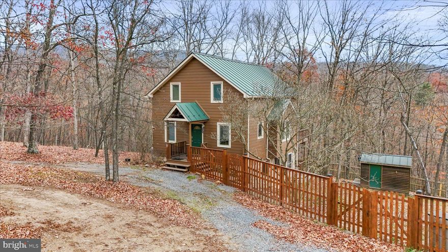 Welcome to Crossings View! This beautiful home, nestled on top of the Cacapon Mountain is more than just a cabin! Topping the ridge you are greeted with this 3 bedroom home and large 2 car garage with additional living space and bar/studio! Inside the home take in the natural light, the views, vaulted ceilings and open concept! The open concept kitchen, living room and dining room are complimented by the beautiful hardwood floors, an eat-at kitchen island with range, a main level bedroom and bath, the floor to ceiling windows in the living room overlooking the deck and yard, and the separate dining and breakfast area! Upstairs is the primary suite with a lofted living area, perfect for additional gathering space, office or personal hang out space. Onto the lower level, the third bedroom and bathroom are paired with a family room/great room and laundry room. The lower level has it's own entrance and deck as well as a gas stove and storage making a great option for an in-law suite or additional living space! Each level of this home feels like it's own personal area making it great for family trips, having guests or just enjoying your own time! As if the home doesn't offer enough space, the garage an incredible addition! This 2 car garage with front entrances has plenty of additional space as well as a bar and a gorgeous studio apartment! The studio apartment is completed with hardwood floors, a tile surround bath/shower, recessed lighting, and is prewired for a home theater! As you step back outside and take in the home and garage, you can admire the large lot, the views, and even the cedar fenced portion of the yard ( 0.5 acre), the shed and the back up generator! Whether you are looking for a forever home, a mountain escape, an investment or even a retirement home Crossings View has so much to offers! The gated community is packed with neighborhood feels, pavilions, river access for kayak & canoeing, basketball courts and plenty of common areas! Take in the peace and quiet of the woods, rivers and mountain while being close proximity to WV, VA and MD; as well as major routes and highways like 522, WV-99 and I-81! **Ask how the UTV could be yours as well