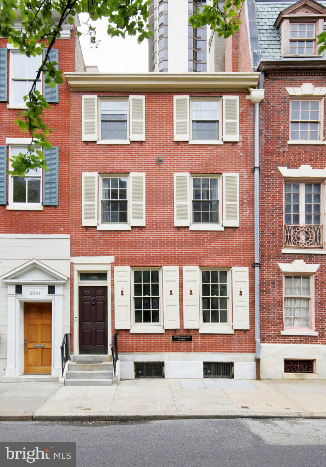 Location, Elegance, History, Space, and Style. Historic Philadelphia meets Contemporary Center City at 2039 Locust. Built in 1853 and situated just a block and a half from Rittenhouse Square, this home, adorned with silhouettes of violins in the exterior shutters and iron railings, was once the workshop of 4 generations of violin makers William Moenning and Son, that were in business beginning in 1909 and occupied this property from 1938-2009. Since then it has been updated into a wonderful, contemporary, single-family home, while still containing original details dating back to its 1853 origins. This 18' wide x 90' deep street-to-street property has all the space you need whether your lifestyle includes entertaining, working from home, raising a family, out-of-town guests, or any combination of the above. Traditionally thought of as having 5 bedrooms, 4 full baths, and 2 half baths, consider its possibilities as a 3BR home with an office and a second living space on the 3rd floor. Enter the home through a beautiful leaded glass embellished foyer into a wide living room centered by an early 20th Century fireplace surround with a Portoro marble slip, flanked by plaster paneled walls, modern wall sconces, and north and south-facing windows. A plaster roundel is centered in the ceiling supporting a George Nelson designed pendant light. Oak floors with walnut inlay run throughout the house. A wide hallway leads past a coat closet and a powder room to a grand, quarter turn, staircase illuminated by multi-pane and fanlight windows. Just beyond the staircase is a spacious dining room with a wide bay window, Art Deco style chandelier and wall sconces, and a wall-mounted and illuminated stained glass window display. The dining room opens to a lovely and large kitchen featuring floor-to-ceiling white cabinetry, many with backlit glass fronts, including one set with a reproduction of a Matisse work on the glass. There is also a blue glazed subway tile backsplash, a peninsula for casual dining, and a frosted exterior door leading out to a very private brick-walled patio with room for grilling, plantings, and seating. The entire second floor is a dedicated owners' level. A very large bedroom is at the front of the house and features another early 20th-century fireplace surround (this one with a brass insert), contemporary wall sconces, south-facing windows, and an ensuite bathroom with a lovely double vanity, oval mirrors, and a marble-tiled and frameless glass shower. Opposite the bedroom is a wonderful office (or nursery) space, with built-in cabinetry, wooden louvered interior shutters, north and east-facing windows, and a nice-sized closet. Between the office and the bedroom is a large walk-in closet, and a marble tiled room that serves as both a 2nd bathroom on the floor with a frameless glass shower, as well as a laundry room. The third-floor front bedroom is as expansive as the owners' suite. It is an extraordinarily fine 2nd bedroom, and would also serve well as a 2nd living space for media viewing and other activities. It features a marble tiled ensuite bathroom. Down the hall is a beautiful interior bedroom with a lovely period chandelier and east-facing windows. The rear bedroom has generous space for a queen bed, plus additional furniture. The fourth full bath is off the hallway and features marble tiled walls and a cast iron tub and shower. A hidden door in the living room wall leads to a finished area of the basement that includes a wine cellar, a room suitable for a playroom or media room, and at the rear of the basement is a large storage/workspace, with workbenches dating back to the days of violin making in this exceptional property. Seller is offering a credit of $4,200 towards the cost of a parking spot for 12 months in a nearby garage or lot. If you are looking to live in the heart of the city, in a place of history with a lifestyle designed for today, 2039 Locust is a property that you do not want to miss.