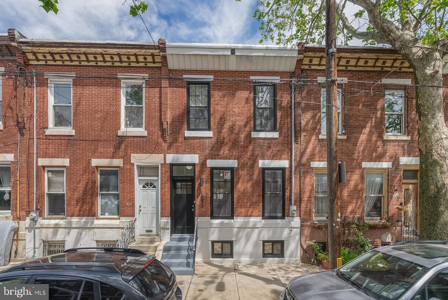 Standing out among the basic renos and new builds, 1533 S Carlisle St is an expertly rehabbed, one-of-a-kind home that offers luxury finishes throughout, abundant space, lots of natural light, and a clean, modern aesthetic. This hidden gem features 4 bedrooms, 3.5 bathrooms, a finished basement, and a private patio, all set on an extra-deep lot, just off Broad St in sought-after Point Breeze. A quiet, tree-lined block leads to the exterior's handsome brick facade and raised entry. Inside, you're welcomed by a vestibule adorned with a distinctive geometric tile floor, while gleaming hardwoods stretch across the open and airy main level, framed by soaring ceilings. At the front is a bright living room with a pair of tall windows, a ceiling fan, and ample space for entertaining. Past a powder room and coat closet, the large dining room is made for hosting family and friends. The heart of the home is sure to be the showstopping, gourmet kitchen that mirrors the pages of an architectural magazine. Boasting white shaker cabinetry, quartz counters, top-of-the-line stainless steel appliances, including a wine fridge, a massive island with seating, pendant lighting, and tall windows, this sunlit space will be the backdrop to many holidays, gatherings, and delicious meals. Out back, the private patio acts as an escape from the city's hustle, perfect for summer barbecues and al fresco dining. More living space is found in the expansive finished basement. There are two large flex areas, ideal for a playroom, home theater, gym, or hobbies, a wet bar, a full bathroom, and a spacious bedroom. Up on the second level, the bright primary suite at the front has two tall windows, a pair of double closets, and an attached spa-like bathroom featuring a double vanity, a soaking tub, a glass-enclosed rainfall shower, and designer tile. Down the hall is the thoughtfully placed laundry closet, and two more spacious bedrooms flanking another full bathroom. 1533 S Carlisle's utilities include central a/c, gas forced air heat, and electric hot water. In addition to everything inside, this fantastic location earns a Walk Score of 90! Popular restaurants, friendly shops, and local businesses fill the surrounding blocks. Parks and playgrounds are close, and neighboring East Passyunk has lots to explore. Stores like Sprouts Farmers Market, Target, PetSmart, and Wine & Spirits are a short walk, plus there's easy access to public transit, Broad St, and Washington Ave. Schedule your tour today!