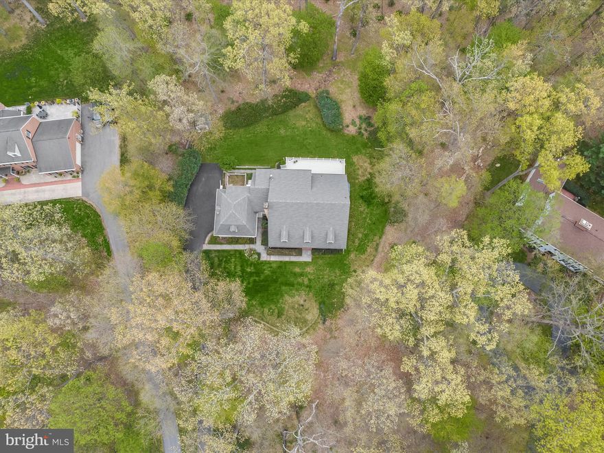 Tucked away on 1.65 acres in the sought-after Goshen Estates community, this custom-built home blends timeless Southern charm with thoughtful design. Inspired by a North Carolina residence featured in Colonial Homes magazine, the home’s architecture draws on romantic Southern influences, complete with a full-width front porch, gabled roofline, and distinctive arched dormer windows. With only its second owners and over 5,400 square feet, this home is rich in character and quality. A long driveway sets a welcoming tone as you approach the home, flanked by an attached carriage-house style garage that adds both function and curb appeal. From the picturesque front porch, step into a two-story foyer where hardwood floors, detailed crown molding, and elegant wainscoting immediately highlight the craftsmanship found throughout. To the right, the formal living and dining rooms offer spacious entertaining areas, each with unique architectural features: beamed ceilings, interior shutters in the living room and a bright bay window in the dining room, which also opens to the deck through a sliding glass door. The heart of the home is the kitchen featuring off-white cabinetry with roll-out drawers and some glass-front display cabinets that blend beauty and practicality. Stainless steel appliances, including a double oven and center island complement the kitchen, while the adjacent breakfast area offers casual dining space with views of the backyard. Just beyond, the two-story great room makes a striking impression with its wall of arched windows, a central fireplace, and second-story windows that floods the room with natural light. To the left of the foyer, the family room offers a quieter gathering space with rich wood trim, built-in bookcases, wainscoting, and a fireplace surround that creates a warm and inviting feel. Sliding pocket doors connect it to the great room, allowing for flexibility between open-concept living and more private spaces. The main level also includes a stylish powder room, a laundry room with built-in cabinetry, and a mudroom with access to the casual entrance. Upstairs, the primary suite offers a retreat with hardwood flooring, a large walk-in closet, and an en-suite bath featuring a frameless glass shower. Two additional bedrooms, each with hardwood floors, share an attached full bath that includes a double vanity and a private water room with a glass-enclosed shower. One of these bedrooms offers access to a Juliet balcony that connects to the middle dormer for a unique architectural detail. The in-law or guest suite offers incredible flexibility and privacy. Accessible via the upper level catwalk overlooking the great room or by a separate staircase from the mudroom, this suite includes a large bedroom with gorgeous wide-plank hardwood floors installed by the current owner. Additionally, a spacious dressing area with a built-in vanity leads to the full bath with a sparkling stone countertop. The sprawling unfinished lower level is full of potential and includes garage access, making it ideal for future expansion, a home gym, workshop, or recreational space. Mechanical updates have been thoughtfully maintained, including a three-zone HVAC system for year-round comfort, a new water heater in 2024, an upper-level HVAC system replaced six years ago, and a roof with gutter guards installed in 2022. Outdoors, a large deck extends across the back of the home, offering serene views of the lush, tree-lined property. A fenced garden area is perfect for those with a green thumb, and a storage shed provides additional space for tools or seasonal items. Just minutes away, enjoy local favorites like Butler’s Orchard and Damascus Regional Park, along with shopping, dining, and recreational options. Commuters will appreciate easy access to MD-124, MD-355, and I-270, connecting you to Rockville, Bethesda, and Washington, D.C. This custom home is a rare blend of space, style, and setting, ready to welcome its next chapter.