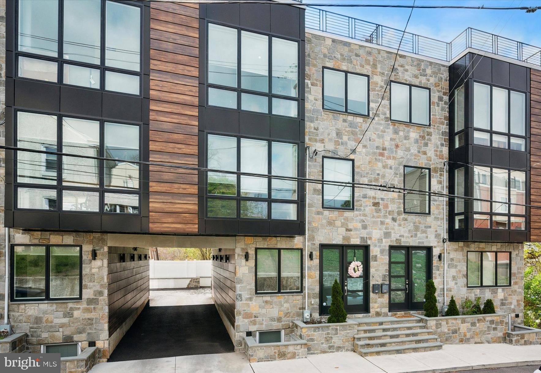 Welcome to 311 Delmar Street, a 2-year young luxury townhome with your dream finishes and amenities. This stunning home with attached oversized 1-car garage features 4 Bedrooms and 4.5 Bathrooms in over 2800 square feet of contemporary luxury space. The first thing you’ll notice is the modern luxe façade, a well-designed combination of stone & wood with contrasting black accents. Drive through the beautiful breezeway to access the garage, a feature that evokes a feeling of security, exclusivity, and privacy. Inside, the design story is a perfect blend of crisp, modern lines and warm finishes which can be the ideal backdrop for a plethora of personal decorating styles. Enter into a large foyer with dramatic 2-story ceilings. An adjacent open space + powder room provide a perfect welcome for guests. Ascend to the fabulous open-concept living floor, complete with a huge living room, kitchen, and dining area that flow effortlessly with each other. A gas fireplace with custom mantle and surround is the focal point of the living area. A chef's eat-in kitchen with white shaker cabinetry, Bosch stainless steel appliances, contemporary white quartz countertops and spacious island ideal for casual dining or entertaining. A wall of sliding glass doors leads out to a balcony with gorgeous leafy trees and skyline views - perfect for summer grilling and relaxing. Large dining area with additional built-in cabinetry and serving area. Upstairs are 3 bedrooms and 3 full bathrooms. Primary Suite features a large bedroom with floor to ceiling sliding glass doors, giving an incredible skyline view from the Juliet balcony. There is also a walk-in closet with custom built-ins, a custom millwork feature wall, and a spa inspired en-suite bathroom replete with radiant floors, oversized step-in shower with frameless glass doors, contemporary double vanity and a glamorous freestanding soaking tub in front of the window with tranquil views makes one feel as though you are in a luxury hotel suite. Convenient laundry room in the hall with side-by-side washer/dryer. Next, you’ll find the Junior Suite with stunning natural light from the oversized windows, as well as an attached full bathroom with beautiful modern finishes. Additional Guest Bedroom with a full bath in the hall complete this floor. From your oversized rooftop deck you will enjoy the incredible Center City skyline and sunset views perfect for entertaining. This will be THE place that everyone wants to gather for the warm weather festivities. Finished lower level is the 4th bedroom... great additional living space that is also ideal for a media room, home office, home gym, play room or guest quarters with full bathroom plus a spacious storage closet. Throughout the home, you will be pleasantly surprised with the upgraded features such as: Sonos ceiling speakers on main floor, custom Hunter Douglas room darkening shades in all rooms, extra thick quartz island top w/ electric and seating for 4, a 5-burner gas stove w/ pot filler, black upgraded hardware throughout, tankless hot water heater, upgraded light fixtures, black iron stair railings, hardwood flooring throughout, wainscoting, roof top deck with electric and faucet, oversized garage w/ epoxy painted floors and EV charger, and coffee bar area in the hallway outside the bedrooms. A truly exceptional home built with only the highest quality building materials in a quiet, private location yet with easy access to Center City, transportation, major highways and the suburbs! 8 years left on the valuable tax abatement! Delmar Place is a special collection of 3 custom city townhomes situated in a very desirable location high in the hills above Manayunk, with NO HOA fees. Don't miss the video tour link. Schedule a private tour today to experience the luxurious details of this unique home!