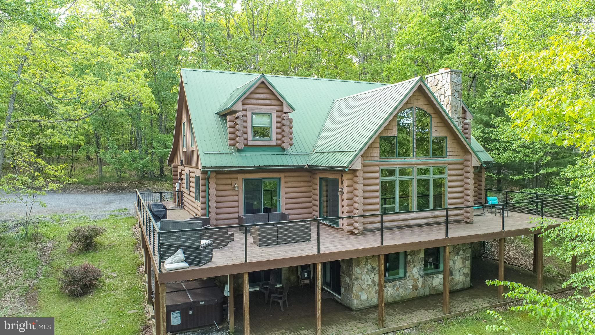 Discover the perfect blend of rustic charm and modern luxury at 425 Hines Drive In Northglade Hills. This is a proven vacation rental named Ar'ya Relaxed Chalet, a stunning five-bedroom, four and one half-bathroom log-style home located in the desirable North Glade Hills community on Deep Creek Lake. This beautifully maintained lakefront property offers year-round enjoyment with spacious living areas, private lake access, and upscale amenities—ideal as a full-time residence, vacation home, or investment opportunity. Set on a picturesque, wooded 1.62 acre lot with 162 feet of lake frontage, the home welcomes you with cathedral ceilings, exposed beams, and a dramatic wall of windows in the great room that floods the interior with natural light. The open-concept layout includes a warm and inviting living space anchored by a stone fireplace, creating the perfect gathering spot in any season. The main-level primary suite is a true retreat, complete with a gas fireplace, a jetted soaking tub, a walk-in shower, and direct access to the expansive deck. Four additional bedrooms—including one with a private bath and others well-suited for guests, children, or use as a home office—offer flexible living options for any lifestyle. The fully equipped kitchen features stainless steel appliances, abundant cabinetry, and generous counter space, making it ideal for both everyday living and entertaining. The adjacent dining area opens to a wrap-around deck, seamlessly connecting indoor and outdoor spaces and offering scenic views of the surrounding trees and lake. On the lower level, a spacious family and game room offers , an incredible wet bar for entertaining, a pool table, shuffleboard, and multiple mounted televisions—creating the perfect space for relaxation, recreation, or hosting guests. Just outside, the lower patio provides access to the outdoor hot tub and a beautifully landscaped fire pit area overlooking the lake, perfect for evening gatherings under the stars.
A gently sloping path leads from the home to the shoreline, where a dedicated boat slip awaits—ideal for boating, swimming, or simply enjoying the calm waters of Deep Creek Lake. The home is situated on a private, quiet street within a well-maintained community, offering privacy and convenience, with easy access to local amenities. With over 4640 square feet of finished living space, two fireplaces (gas and wood-burning), a gently sloping driveway with ample parking, and a proven history of vacation rental income potential, Ar'ya Relaxed Chalet is a rare opportunity to own a lakefront gem in one of Western Maryland’s most sought-after destinations. Conveniently located just minutes from Deep Creek Lake State Park, Wisp Resort, ASCI, local dining, shopping, and year-round outdoor recreation, this home truly has it all. RAILEY REALTY IS NOT THE CARETAKER OF PROPERTIES LISTED BY IT. DURING INCLEMENT WEATHER CONDITIONS, PROSPECTIVE PURCHASERS AND THEIR AGENTS ASSUME ALL LIABILITY ASSOCIATED WITH OR BY WEATHER AT THE PROPERTY.