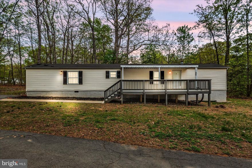 Manufactured single-wide home on just over 1 acre with a mix of open and wooded land. Features a partially covered front porch, rear deck, two sheds, and a carport. Large blacktop driveway offers ample parking. Interior offers 2 bedrooms and 2 full baths, including a primary suite with soaking tub and separate shower. Washer and dryer convey. Kitchen includes dishwasher, refrigerator, oven, and built-in microwave. Conveniently located just 2 miles from Lake Anna State Park.