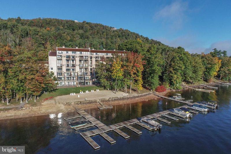 Presenting a unique lifestyle opportunity on Deep Creek Lake at Will O' the Wisp Prestige Condominiums, unit D310/410. This is a 2-bedroom, 2-bathroom condo with a bonus room. Full time in-residence owners completed total renovations of the condo & each room includes upscale finishes & tasteful decor. Upgrades include 2 hot water heaters, updated/expanded electrical system, private WIFI/cable and 2 HVAC systems resulting in energy efficiency and lower electric bills. The "D" units are highly sought after as there are only four "D" units in the building. The bonus room is currently being used as a pantry and laundry room. Notably, this is the only condo that offers an in-unit washer and dryer. The condo boasts not one but two fireplaces and two lakefront balconies. The 2nd bedroom is being used as an office with continued expansive lake views. An end unit, providing more privacy as well as easy access to the 4th floor entrance to/from the parking garage. The building has undergone numerous updates, including new hallway decor, flooring, furnishings in the common areas, parking deck, Social Room and lakeside balcony remodels are underway. Amenities include an indoor heated swimming pool, a two-tier spa, sauna, indoor racquetball court, arcade game room, fitness facility, a building elevator servicing the seven floors of the building. Additionally, 240 ft private beach and 22 slip boat dock. 30 garage and 30 street level parking spaces. The location and convenience of these amenities, coupled with the two lakefront restaurants, Aces Run and Firewater, makes this a popular destination for private use of the condo or as an income producing rental property. Don't miss out on the opportunity to tour this unique lakefront condo and experience the beauty of Will O' The Wisp.