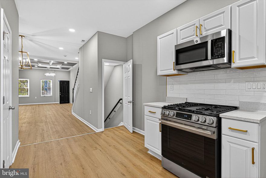 Experience the perfect blend of sleek design and home comfort in this stunning, newly renovated Baltimore townhome. Every detail has been meticulously curated to offer a turnkey residence that is both high-functioning and aesthetically beautiful.  Stepping inside, you are greeted by an expansive open-concept living area. Your eyes will immediately be drawn to the impressive architectural details:
A dramatic, dark gray geometric wood slat panel system provides a sophisticated backdrop.
Look up to find custom coffered ceiling trim, expertly painted with a charcoal accent, housing modern recessed lighting and anchored by a striking, minimalist glass chandelier.
Light-oak luxury plank flooring flows seamlessly through the space, providing durability and warmth.
The kitchen is a functional work of art, designed to impress the home chef. It’s defined by a stunning corner wood-accent slat wall that complements the main living area. Brand new, fingerprint-resistant stainless steel Whirlpool and LG appliances. Bright white Shaker cabinetry is paired with dramatic, custom matte gold hardware pulls, adding a touch of glamour. Sleek Carrara-style quartz countertops and a glossy white subway tile backsplash complete the look. Follow the stylish black and white contrast staircase to the second floor, a sun-drenched hallway  leading to serene personal spaces.
Spacious secondary bedrooms feature new carpet, fresh paint, and ample natural light.
This stunning full bath is a masterpiece of design. It features dramatic full-slab faux-marble walls, a massive black hexagonal-tiled shower niche, a sleek black-framed mirror, and modern black matte plumbing fixtures. The room is anchored by parallel wood slat paneling flanking a soft sage-green feature wall. The ultimate in luxury. This bathroom showcases a gold-trimmed mirror, gold plumbing fixtures, and a unique gold hexagonal tiled shower niche. The property’s features extend downstairs to a versatile and bright fully finished basement: The rear exit opens to a private, fully fenced-in patio, featuring clean gravel landscaping. It’s the perfect spot for container gardening, morning coffee, or safe outdoor play, offering a peaceful escape from the city hustle.
Don’t miss your chance to own a home that truly stands out in the marketplace.
Schedule your showing today! This property won’t last long.