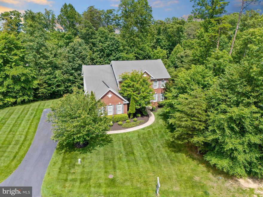 Welcome to this rare opportunity to own a home in the private and quiet Occoquan Overlook neighborhood of Lorton! 9053 John Sutherland Ln is ready for you to make it your own. This home boasts over 5,000 square feet of living space on just under an acre. Upon entering the two-level foyer, you are greeted with a large sitting room and dining room with access into the main living space. The open concept living, kitchen, dining area is spacious and expansive. French doors lead into the main level office and a large slider leads onto the back deck, where there is a gas hook-up for your grill and stairs to access the tree-lined yard. The hardwood floors have been impeccably maintained, and the carpet on the main levels was recently replaced. The entire home is a blank slate, ready for you to make it your own. Take the front or back staircase up to the second story landing of the home. Off the landing, double doors open into a versatile bonus room/flex space. There are three bedrooms, one with an en suite bathroom and two that share a Jack-n-Jill bath. The upstairs laundry room provides convenience and storage. The large primary suite boasts plenty of space for a sitting area, a large bathroom with two vanities, a soaking tub, shower, and toilet room. Additionally, there is an extra storage room and expansive closet.  All closets on the upper level feature custom closet systems to maximize storage and organization. Additionally, the home is outfitted with long-lasting Andersen windows and plantation shutters throughout. In the basement, there is a large game, recreation area, as well as a huge storage space with a secondary washer and dryer hook-up. With a fifth bedroom and full bathroom, as well as a full second kitchen and walkup to the yard, this basement could function as an in-law suite or just an incredible entertainment space. This home is a beautiful blank canvas, waiting for its new owners to make it their own!