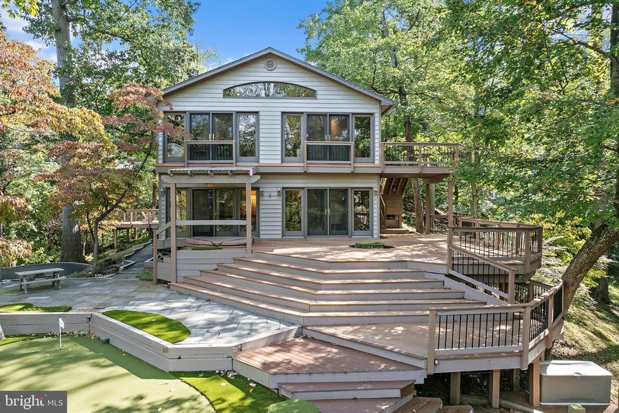 Nestled into the tree tops off a private drive in highly sought after Winchester on the Severn, this mid century raised rancher will check all your boxes. From the moment you pull up the private drive to the home, you are immediately at ease.  Step out of the car to the sounds of birds and the rustle of the trees. You will feel as though you have escaped it all, yet you are right in the heart of Winchester, a quick drive from Historic Downtown Annapolis and a stones throw to the famed B&A trail. As you enter the front walk, you will be immediately struck by the quality of craftsmanship and materials on the exterior of the home.  Once inside, the rich wood beams, wood trim and floors strike a dramatic combination with the soaring ceilings. The abundant windows and doors leading out to the sunroom will ensure that the beauty of the natural surroundings take center stage. The chef's kitchen is equipped with granite countertops, a deep sink, lovely picture window over the sink, double wall ovens and high end fixtures. The sunroom serves as an additional dining space and relaxing sitting room with full views of the surroundings.  You will feel as though you have escaped to a mountain retreat! The main level offers a full hall bath and three comfortable bedrooms including an owner's suite with ensuite bath and double closets. The fully finished lower level is a lovely living space on its own with a cozy den, office and flexible bonus space that could be a 4th bedroom with its own ensuite bath.  The lower sunroom is the perfect spot to partake in your morning yoga and meander out to the hot tub for a leisurely soak. Entertaining is a breeze with the expansive, multi-level decks and putting green for fun. After a day on the water, use the outdoor shower to rinse away the salt and sand. Winchester offers two beaches (one is referred to as Dog Beach for obvious reasons) and two marinas. The beauty of a water access community on the Severn River is easy access into Annapolis by boat without going out into the choppy Bay.  You can hop on a small tender and dock in town at the dinghy dock for dinner any time you please. Walk or bike up the B&A trail for coffee, ice cream or grab must haves at the gourmet cheese shop.  Brunch at the Severn Inn overlooking the River or pop over to Garten Beer Garden for a lovely supper with friends. This is not merely a beautiful home, this is a highly sought after lifestyle.