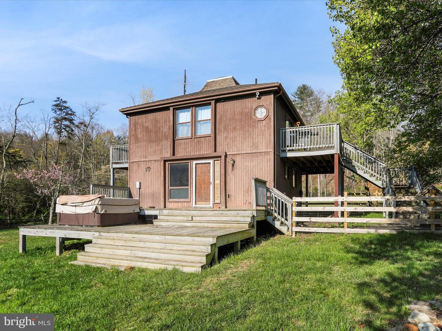 Enjoy your peaceful four-season home on 5 plus acres in the stunning mountains of West Virginia, just a short distance from the Cacapon River, in the desirable gated River Ridge Community, just 2 hours from DC and Baltimore. The home is one of the few homes that boast an unobstructed view of the magnificent Cacapon Mountain from the front deck. Within a short distance to the Cacapon River but not in a flood zone, the 5.61 acres of land has beautiful mature trees and landscaping. Two of the acres are a fenced meadow and the remaining 3+ acres are wooded. 
This 3-bedroom, 1.5-bath home offers a rare blend of privacy, space, and potential.  As one of the original first properties to be built in River Ridge, the home itself is in need of some TLC and updates, but it’s the perfect canvas for someone ready to bring their vision to life. Whether you're an investor, a weekend warrior, or someone looking to create a custom getaway, the possibilities here are endless.  With heavenly views from the upper deck to the wood burning fireplace inside and access to the Cacapon, this home offers lots of possibilities! Enjoy evenings outside around the fire pit or relax in the recently serviced hot tub as you take in the views around you.  The detached garage adds extra value and versatility — great for secure parking, storage, or transforming into a workshop, hobby space, or studio. Whether you're looking for a place to tinker, create, or just keep your tools and equipment protected, it’s a great bonus feature with tons of potential. Great opportunities to enjoy hiking, swimming, kayaking, fishing and the peaceful tranquility the home has to offer.  Home is being sold as -is. Book your showing today!