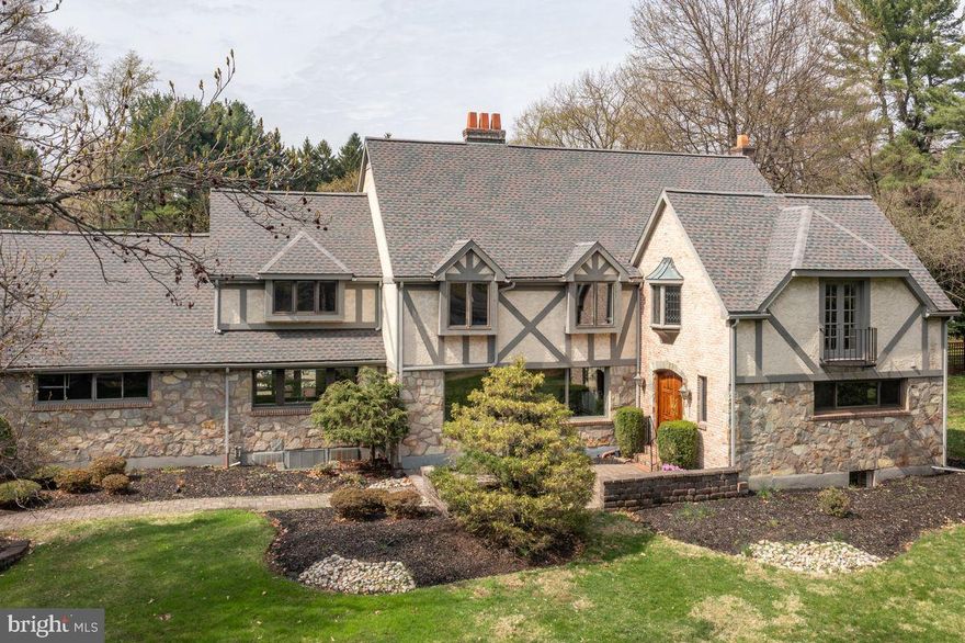 Originally built in 1960 as a classic ranch, this exceptional home was meticulously transformed in 1981 into a stunning Tudor-style residence. Nestled in one of Saucon Valley’s most desirable and established neighborhoods—where each home is distinct and mid-century elegance abounds—this residence offers the perfect mix of privacy, comfort, and convenience, just minutes from Saucon Valley Country Club, shopping, and fine dining. A gracious paver courtyard leads to double arched doors, welcoming you into a marble foyer with wainscoting, chair rail detailing, and dual coat closets. With 4,136 square feet, 4 bedrooms, and 3.1 bathrooms, the home's layout offers spacious, light-filled rooms and an effortless flow ideal for both everyday living and grand-scale entertaining. The chef’s kitchen, fully renovated in 2022, is a standout with custom cabinetry, quartz countertops, Sub-Zero refrigerator, Wolf propane cooktop and double wall ovens, microwave drawer, Summit wine fridge, and walk-in pantry. Glass door lead from the sunny breakfast area to a serene terrace overlooking the pool. The formal living room features a dramatic wall of windows and a stone fireplace, opening seamlessly into a large dining room with sliding glass doors to the outdoor grilling station with granite countertop. The library with coffered ceiling and pocket doors sits just off the foyer and offers a stylishly renovated full bath with porcelain tile and LED mirror. The family room is equally inviting, offering a paneled fireplace, dry bar, and custom built-ins. Upstairs, the primary suite is a true retreat, with vaulted ceilings, exposed stone detailing, a sitting area, and dressing room. The en suite bath boasts Devon & Devon fixtures, antique brass swan taps on the jacuzzi tub, and separate glass shower. A nearby laundry room includes a cedar closet. Down the hall are three additional bedrooms, two with vaulted ceilings and skylights and one with built-ins and a charming Juliet balcony overlooking the expansive front lawn. The newly-renovated hall bath offers double quartz vanity, glass tub/shower doors, new porcelain tile floor, new lighting and electronic Brondell bidet seat. The bonus room is the ideal computer nook or storage. Outdoors, enjoy the beautifully landscaped and fully fenced backyard featuring a private pool, a freshly painted cabana with new wet bar and beverage fridge, and approx. 2,000 sf of paver patio. Towering pines, tulip trees, and fruit trees provide shade and privacy, all protected by hand-forged wrought iron gates and mature Leyland pines. Additional features include: 2023 roof, whole-house generator, System 2000 boiler with 4-zone baseboard heat, solid wood interior doors with brass hardware, abundant closet space, full basement with waterproofing system. Located in the Blue Ribbon Saucon Valley School District, this warm, inviting, and well maintained home offers the rare opportunity to enjoy classic Tudor beauty with modern luxury in one of the Lehigh Valley’s most sought-after areas.