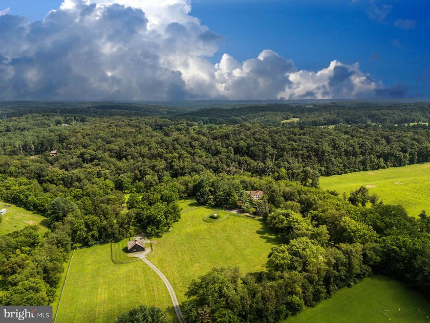 Live authentically. Stones Throw Farm. Set in the heart of Greenspring Hunt Country, this exceptional 18.01 acre estate offers unrivaled privacy amid gently rolling pastures. A meandering tree-lined drive heightens your sense of arrival, as sweeping panoramic views unfold all around. The landscape is embraced by a meandering stream on three sides with walking trails... quite remarkable. The plantings are masterfully composed, framing epic sunrises and sunsets. The home’s architecture balances rustic authenticity with refined comfort. A first-floor primary suite with spa bath features premium views of your beloved animals in the pasture beyond. The expansive cooking space invites convivial gatherings, opening seamlessly to a generous deck and patio designed for effortless entertaining. A state-of-the-art equestrian barn over-engineered where supreme functionality meets beauty. Bespoke chicken coop redefines pastoral indulgence. Here, the rhythms of nature shape daily life—birdsong at dawn, open skies at dusk, and the abiding calm of land and water in perfect harmony. Stargazers rejoice... your very own celestial observatory. Take photos and ponder the cosmos. Xfinity Internet. Cultivate your existence. The art of uniting human and home.