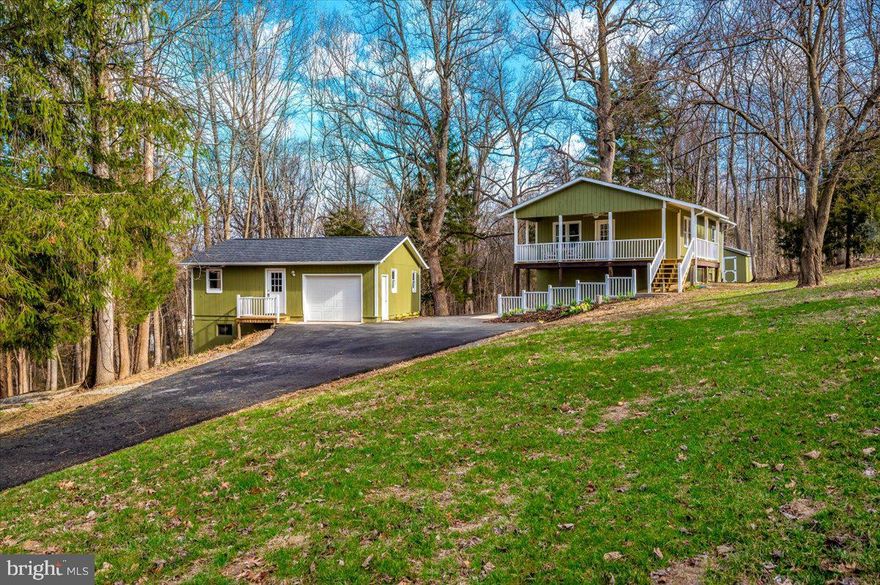 Welcome home! We were off market for a few days to brighten the basement!  In addition to the natural beauty of 5.37 mostly-wooded acres, you score a beautifully-updated 2 bedroom, 1 bath cabin/cottage, a detached garage with a huge workshop/office, a gazebo tucked in the woods, and an upscale chicken coop/storage shed.  Look for white ribbons that mark approximate property lines. The newly-paved driveway welcomes you on the left.  Once in, the cabin is on the right and the garage/workshop/bonus room is just to the left.  The gazebo is tucked in the woods and the coop/shed is just beyond the house.  Walk up a few steps to the large front porch to the enter the cabin.  The light-filled open-concept living area welcomes you. To the left, the kitchen features beautiful, quality, white cabinetry, stainless steel appliances and gorgeous granite counters. Enjoy the table space next to the windows or enjoy extra seating at the extended granite counter.  New Bellawood (real) hardwood flooring and neutral paint run throughout the home. To the right is a welcoming family room. A new electric fireplace with pretty white mantle makes for a cozy, mess-free ambience.  Past the main living space is laundry room, bathroom, and two bedrooms.  The laundry room features the same beautiful white cabinetry used in the kitchen, including a pantry, and a new washer and dryer.  There is a coat and seating nook tucked just off the family room.  The bathroom has been updated from floor to ceiling.  The tub with shower is surrounded by white subway tile.  Even the fan is pretty and quiet.  The two bedrooms are cozy and perfectly suited.  Heat and a/c are provided by a new Trane heat pump/air conditioner.  The roofs on all buildings are new architectural shingle, except for the shed (it has a nice metal roof).  The basement is the same size at the main living level and has an at-grade walk-out to the back yard.  Freshly painted with vinyl plank flooring. It houses mechanicals, a work sink, a wood stove, and so much space for future rooms.  The detached one-car garage is slightly-oversized with workbench and adjoins the home workshop/office.  The garage houses a separate breaker box.  Thoughtful placement of outlets and overhead lighting add to the appeal. The workshop/bonus room is huge.  It has  nicely-finished walls, multiple windows, a new mini-split, and commercial-rated luxury vinyl plank flooring.  The lower level of this building features another workshop plus a storage area.  The gazebo sits in the woods inviting picnics, play, or tranquility.  When you want to explore beyond your 5.37 acres, you can enjoy two community-owned areas.  One is 42 acres (just steps away from your property line) and runs along Sharman’s Branch, which connects to Antietam Creek.  The other is 32 acres along Antietam Creek, just down the main neighborhood road.  Enjoy fishing, rafting, canoeing (on the Antietam), or a stretch of the legs.   Enjoy local amenities and nearby attractions too—Antietam Battlefields, historic Sharpsburg or Boonsboro, Shepherd University, C&O canal, wineries, restaurants, and more.  Commuter routes are nearby too.  The HOA does an admirable job on snow plowing too! Be who you want to be—entrepreneur, hobbyist, retired, work from home, entertainer, weekend retreater, solitude seeker—this little piece of paradise does it all.