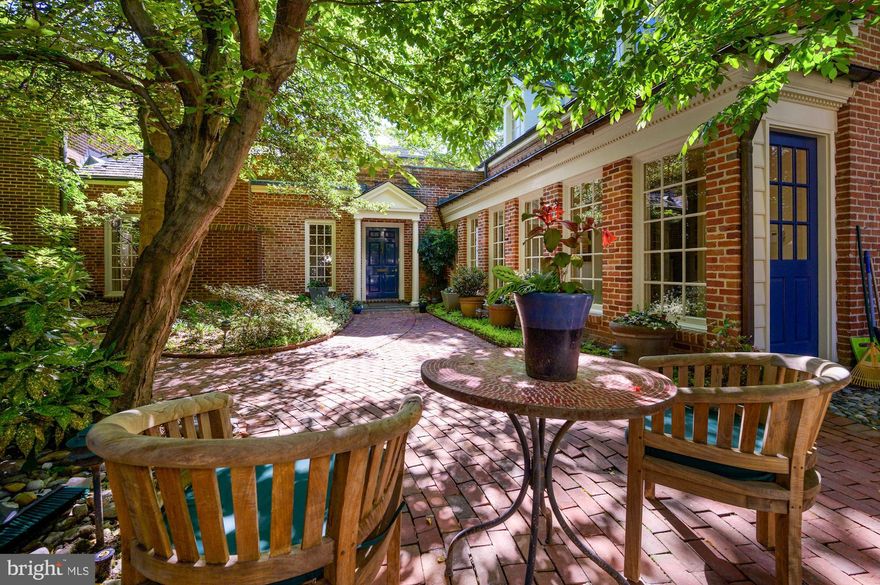 The home at 2750 Q Street is a rare jewel in historic Georgetown’s East Village. Set well back from the street behind a handsome wrought iron gate, it is exceedingly private and almost invisible to passers-by. The property was originally owned by the American diplomat and philanthropist Robert Woods Bliss and his wife Mildred, who also owned and developed the estate at Dumbarton Oaks to house their extensive art collection. 
The current home is beautifully designed, with lovely architectural detailing and large windows overlooking multiple terraces and outdoor seating areas. Its versatile floor plan makes it an ideal home for different family configurations. On the entry level are elegant living and dining rooms, a generously proportioned kitchen with adjacent breakfast room, a powder room and a spacious office with a full bath that could also be used as first floor bedroom suite. There is a separate bedroom wing on either side of the house: a primary suite, accessible by ELEVATOR or stairway, on one side, with a luxurious bath and two walls of closets; and two additional bedrooms with a full bath, reached by a second staircase on the other side of the house. The arrangement allows for maximum privacy and flexibility, and is ideal for houseguests, older children or live-in help. The home has lush green views from almost every window, landscaped terraces in front and on either side, and a private DRIVEWAY with space for 2 CARS. This is an extraordinary property, beautifully situated in one of the city's premier residential neighborhoods.