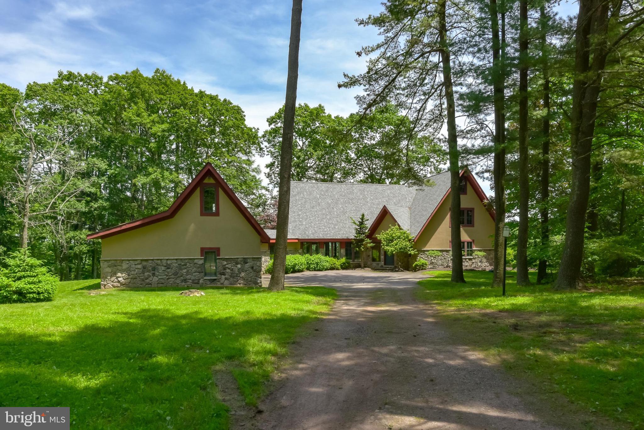 A long, curved driveway leads to Strawberry Hill, located in Sweet Valley, Pennsylvania. Named for the wild strawberries that grow on the property, this magnificent home is set on nearly 50 acres of open fields and mature woods. This architecturally unique residence was built in the 1950s and extensively expanded and renovated in the mid-2000s. The light-filled home features a vaulted ceiling with a stone gas fireplace and a live edge cherry mantle in the sunny family room. Beautiful cherry millwork and locally sourced cherry flooring on the first floor, oak on the second, flow graciously throughout the home. The gourmet kitchen with spectacular large gold granite central island is a gathering space complete with modern stainless appliances and cherry cabinets. The dramatic dining room overlooking the private grounds offers wonderful entertainment space and connects to one of the two outdoor terraces. An original brick fireplace with an artisanal cherry mantle graces the dining room. Underneath an adjacent long bank of windows, a graceful live edge cherry work shelf is an ideal spot for a morning cup of coffee and a good place for working on a laptop. In springtime there are breathtaking views of forsythia and hundreds of daffodils. The adjoining library/office features warm hand-crafted cherry wood paneling, a third gas fireplace with cherry mantle, and ample space to curl up with a good book. The second floor offers a beautiful primary suite complete with raised ceiling and rustic hand-hewn beams, private marble and granite bathroom, and views of the nearby woods and distant hills. Three additional bedrooms offer guest space. A large three-car garage and two wonderful patios complete this stunning estate. Strawberry Hill is a must see.