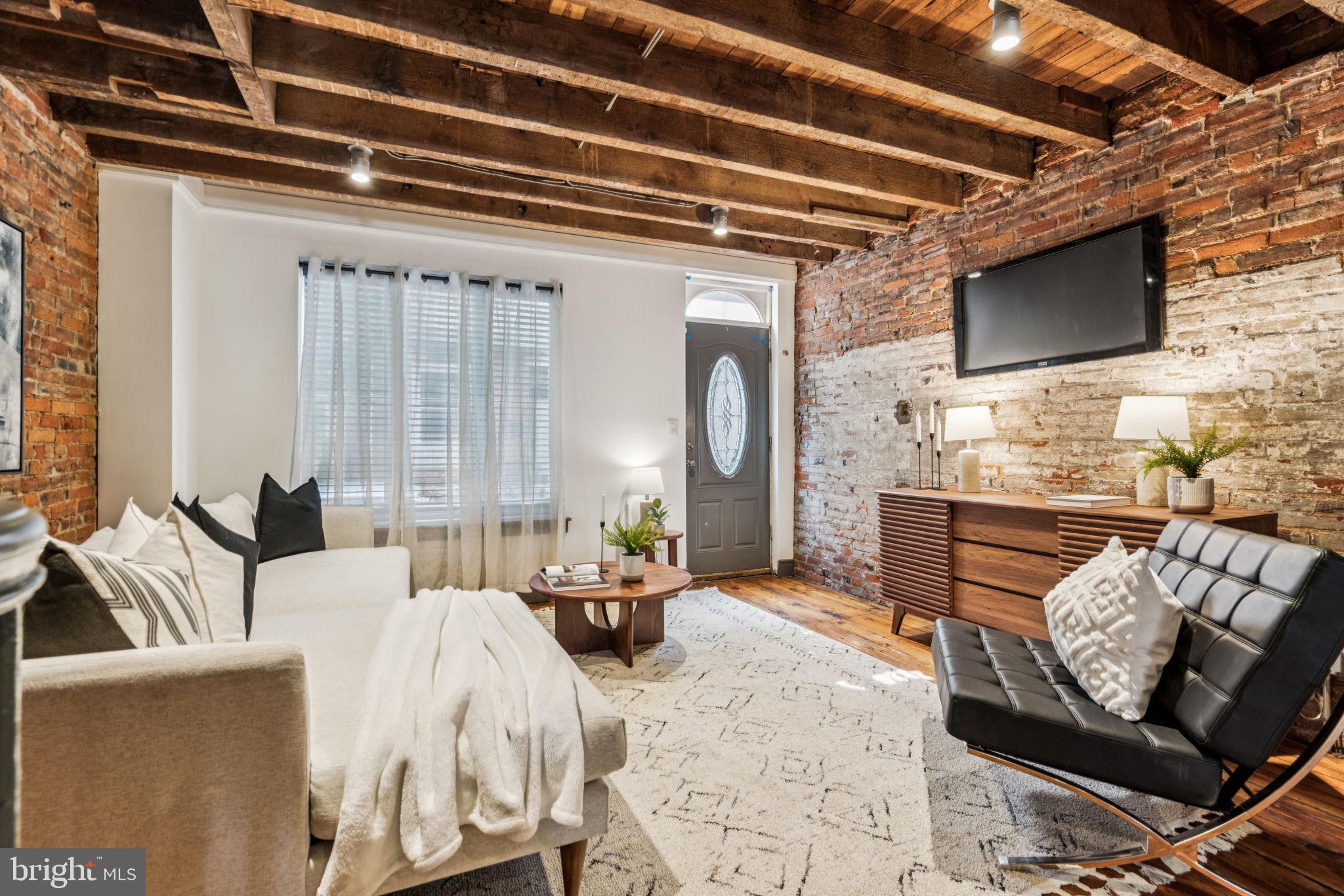 Breathtaking 1800s architectural bones meet contemporary updates in this beautiful three-bedroom, one-and-a-half-bathroom townhouse featuring chic interiors, a detached garage, and a private backyard on a block-through lot in South Philadelphia's vibrant Passyunk Square neighborhood.
Inside this truly unique home, exposed timber beams soar over refinished original wood floors and rustic brick walls, while dimmable lighting and stylish paint add a designer ambiance throughout. On the first floor, the open layout flows from the spacious living room to an inviting dining area flanked by a convenient coat closet and a windowed powder room. Ahead, the work-of-art kitchen impresses with custom cabinetry, industrial open shelving, gorgeous marble countertops, and a fleet of high-end appliances, including a vented maroon Ilve gas range, vent hood, French door refrigerator, and dishwasher. Enjoy casual meals at the large center island breakfast bar or step out to the adjacent west-facing rear yard for al fresco dining and entertaining.
Head upstairs to explore the serene primary suite featuring a king-size bedroom, an oversized dressing area, and pocket doors that open to the semi-private bathroom, also accessible from the hall. Inside the beautiful bath, floor-to-ceiling marble tile and polished chrome hardware surround a handsome console vanity and large rain shower with a bench and window. The spacious and bright secondary bedroom on this floor boasts a designer wallpaper mural and a roomy closet. Head to the third-floor loft to find a flexible space perfect as a third bedroom, home office, guest area, family room, or whatever your needs require.
The large basement provides generous storage space and a laundry area with a side-by-side washer-dryer and freezer. Enjoy even more storage and off-street parking in the large garage accessible from Reed Street. Updated electrical and plumbing, and central HVA,C complete this turnkey historic townhouse.
Located on a charming Passyunk Square street, this fine home is surrounded by some of the best shopping, dining and nightlife in South Philly. Enjoy neighborhood favorites like Comfort & Floyd and Triangle Tavern, plus the Philly icons Geno's, Pat’s and the Italian Market minutes away. ACME Market is right across the street, and playgrounds, parks and dog parks provide fantastic outdoor space. Transportation is effortless with the Tasker Morris SEPTA Station, excellent bus service and freeways all nearby.
