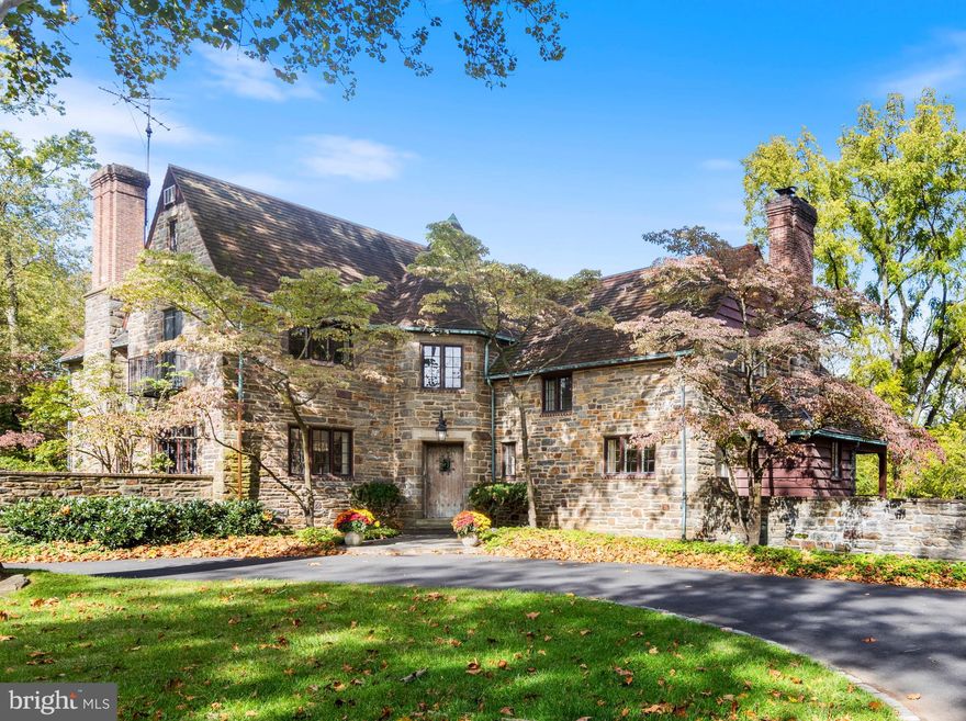 Welcome to the Arthur Brockie house! Arthur Howell Brockie, a prominent Philadelphia architect, had an illustrious career designing hospital, banks & estate homes in the area. His notable architecture includes the iconic Sedgley Club & lighthouse on the Schuylkill River, the Philadelphia Zoo’s Bird and Reptile Houses & the clubhouse at Philadelphia Cricket Club. in Chestnut Hill. In 1930, Brockie designed his personal home on 3.8 acres above the banks of Lorraine Run that flows into the Wissahickon. Down a long driveway to a circle drive with a stately sycamore tree, the French Normandy style Pennsylvania fieldstone & brick house is sited for southern exposure that provides an abundance of natural light. A detached, 2-car garage was updated with an efficient 1-bedroom apartment. Stone walls extending from the house provide an understated backdrop to perennial border gardens. A flagstone walk leads to a handsome English Tudor style oak door with original lighting & iron details within an octagonal turret. The roof showcases original Ludowici terra cotta tile. Inside, a gracious foyer with original sconces connects the family, living, and dining rooms. An arched Dutch door leads to an elegant flagstone terrace that connects to the courtyard and overlooks a pond, ringed by mature trees, and a massive backyard. The random width & pegged oak floors extend into the living room, the dining room, and up the wraparound staircase and landings. The 1st floor boasts many interior and exterior French doors, making the house ideal for both intimate and large gatherings. Original banks of Hope’s steel & bronze casement windows and French doors, as well as original solid wood doors with brass hardware remain throughout. It’s believed Brockie repurposed a ship’s ballast stone for the window sills in the family room & entry. A Murano glass chandelier adds a touch of whimsy. The living room with original unpainted natural wood paneling is anchored by the wood burning fireplace. A lovely light filled dining room has a  bay window with period tile sill & a French door that leads to the terrace and backyard. A 2nd Murano chandelier provides colorful light over a massive table that hosted many impromptu and large holiday gatherings. Purchasing the home in 1961, the current owners, pillars of the local business & philanthropic communities, lovingly made this their home for 62 years. Keeping the integrity of Brockie’s footprint, the kitchen was renovated in 1965 into a free-flowing kitchen, bar, breakfast room, and mudroom area. Windows provide an expansive view of the backyard where tented celebratory events, neighborhood football & baseball games, and friendly competition on the ½ basketball court played out. A staircase accesses the full basement and 2nd floor. The working “call bells” bear the architect’s name.  A powder room & coat closet complete the 1st floor. At the top of the main staircase are 3 large bedrooms. The 1st bedroom has been a nursery (connected to the primary) & was modified to a home office. French doors open to a Juliet balcony above the courtyard. The primary with original fireplace and dressing room, has an ensuite bath with original fixtures. The primary was enhanced with a wall of windows, slider & balcony that overlooks the pond where summer canoeing & winter ice skating parties were routine. The 3rd bedroom sits atop the dining room with views of flowering trees on the terrace and a majestic black walnut tree in the backyard. It has an ensuite bath that can also be accessed from the hall. Two charming bedrooms, an original walk-in linen closet with laundry chute, and a 3rd full bath complete the 2nd floor. A hall door hides a seemingly secret 3rd floor with a 6th bedroom, an adorable Bunk Room reminiscent of the Poconos, and a 4th full bath. Meticulous in its architectural details and quiet elegance, the Arthur Brockie House is a bucolic respite that is a world away, yet around the corner from everything!