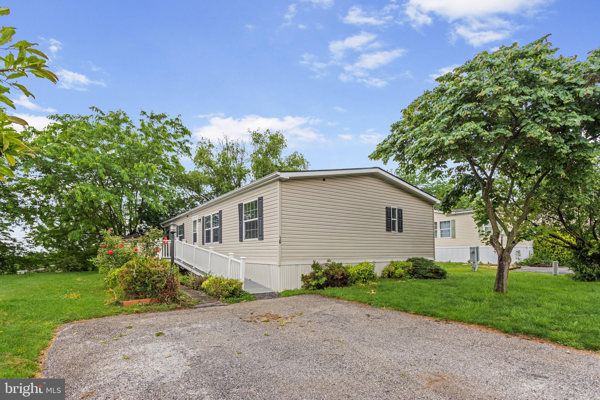Looking for comfort and convenience with a great view? This 3BR/2BA doublewide home boasts easy living with everything on 1 level. Extending from the 2-car parking pad, there is a low-maintenance composite ramp that leads directly to your front door. As you step inside, you are greeted with a bright, open living space overlooking the kitchen and dining area. At one end of the home is your primary bedroom & bathroom complete with a spacious walk-in shower and easy access to the laundry area. At the opposite end are 2 additional bedrooms with large closets and a 2nd full bathroom with a tub/shower. Enjoy additional outdoor living space on your covered deck overlooking the community. Kitchen refrigerator, range/oven, dishwasher, washer, dryer and shed are included. Also included is a 1-yr home warranty with First American.