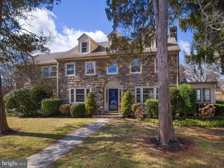 Discover the perfect blend of timeless charm and modern living in this stunning center hall stone colonial. Boasting six bedrooms and 4.5 baths, this home welcomes you with a grand foyer featuring elegant archways and wainscoting. The spacious living room, complete with a gas fireplace, is ideal for gathering with family and friends, while the beautifully renovated four-season sunroom offers a bright and tranquil retreat. A formal dining room flows seamlessly into the updated eat-in kitchen, which features custom cabinetry, premium countertops, stainless steel appliances, dual ovens, and a large pantry. The first floor also includes a powder room and plenty of closet space.

The second floor offers a luxurious primary suite with two large closets, an ensuite bath, and a private deck. Three additional generously sized bedrooms, including one with its own ensuite bathroom, provide ample space for family or guests. A hall bathroom and a convenient laundry room complete this level. The third floor adds even more versatility with two additional bedrooms, a flexible space perfect for an office or playroom, and a full hall bathroom.

Outside, the home features a large, fully fenced yard with an automatic gate, two driveways, and an attached two-car garage. A spacious covered patio with an awning is the perfect setting for outdoor entertaining. Ideally located just blocks from restaurants, coffee shops, boutiques, a farmer’s market, and the R-5 train line to the city, this home offers unmatched convenience. With low taxes and a perfect blend of character and modern updates, this property is a rare find.