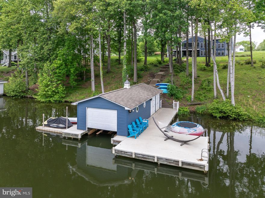 Turn-key, completely furnished waterfront home with high-speed internet now available at Lake Anna!  Located on the water in the popular Wyndemere subdivision on the public side of Lake Anna, this charming lake house sits peacefully in a protected cove with approximately 175 feet of private shoreline, and its own private boathouse with electric boat lift, jet ski pads, storage room for your water toys, large sun deck, hammock for Sunday naps, and maintenance free decking.  Inside the home, large windows invite beautiful water views throughout the main level's spacious open floor plan.  The great room provides expansive space with a fireplace, mantle, built-in shelves/cabinets, and access to a large screened-in back porch.  The upgraded kitchen includes a large island, granite counter tops, stainless appliances, tons of storage space, and a separate eating area overlooking the lake.  The main level also features two large primary suites, both with en suite bathrooms with soaking tubs, double vanities, and separate walk-in showers.   Downstairs, the space is extensive — large entertainment/ movie area, pool table, a premier card table with 6 high back leather chairs, arcade games, and 2 additional bedroom suites.  A brick paver sidewalk meanders down to the water, which offers approximately 175 feet of shoreline, a generous enclosed boathouse with a boat slip with electric lift, floating jet ski pads, sizable storage room, hammock, and big sundeck, all constructed with maintenance-free decking.   Purchase includes furniture, decorations, BBQ, full sized pool table, shuffleboard, 6 foot tournament card table with matching chairs, movie theater, sports equipment and bicycles, water toys, 4 kayaks, 2 paddle boards, lifejackets, tubes, large floating island, hammock, games, signed Star Wars artwork, dog toys, and much more.  Two jet skis for sale separately for $8,000 for the pair.   High speed internet!  Fantastic location: close to groceries, restaurants, The Lake Anna Taphouse, nail salon, vet clinic, fast food and more.   Roughly 45 minutes to Richmond, Charlottesville and Fredericksburg, and just 90 miles from Washington DC.