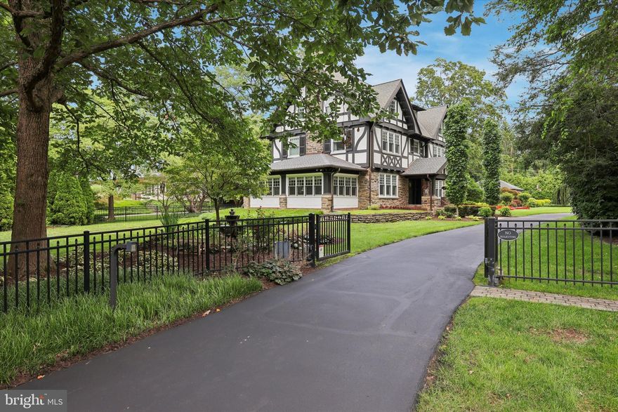 This stunning 1905 Tudor Revival was designed by John Owens for Elizabeth Strawbridge of the storied Strawbridge family. Situated on a manicured 3/4-acre lot in the heart of Chestnut Hill, this property includes 5 spacious bedrooms and 3-1/2 baths, spanning approximately 5,250 square feet. The first floor of the home welcomes you into a grand entry foyer showcasing spectacular original leaded glass details, chestnut millwork, and the lower Inglenook sitting area complete with gas fireplace. To the left sits a living room with custom built-ins and lighting. Beyond the living room is the converted all-season sunroom with heated floors. To the left of the front door sits the formal dining room with ample room for entertaining. The expansive eat-in kitchen includes custom cabinetry,  an oversized banquette, as well as a desk and pantry area. The stainless steel appliance suite includes a gas range in addition to twin dishwashers, one hidden, for ultimate convenience. Toward the back of the home is a thoughtfully-designed mudroom and laundry area, leading out to the breathtaking backyard and large flagstone patio. The kitchen and mudroom floors are heated for year-round comfort. An updated half bath off the kitchen completes this floor. On the second floor, two bedrooms share an updated Jack-and-Jill bathroom with tub and shower. The third bedroom is currently used as a large office with the fourth bedroom serving as a guest or au pair suite with an ensuite bath with double-vanity in white marble. Off this bedroom is a second floor outdoor covered porch with sweeping views of the manicured backyard. The entire third floor is a sumptuous primary retreat. The bedroom spans half of the floor with an ensuite bath, featuring an oversized soaking tub, a neo-angle glass shower with bench, a double vanity, a water closet, and heated floors. The remainder of the third floor is shared by a large dressing room and a bonus room, currently used as a gym with an infrared sauna. The multi-year renovation and restoration was undertaken with meticulous attention to preserving original details while updating to current standards. The home stands move-in ready for its next steward. Thoughtful upgrades include 53 Pella Architect Series windows, while the original leaded-glass windows were spared. Two working fireplaces are highlighted in the living areas (one converted to gas). All electrical and plumbing have been upgraded or replaced, in addition to an ultra-high-efficiency Lochnivar boiler providing heat and unlimited hot water while maintaining low heating costs, plus new central high velocity forced air. An approximately 1,800 square-foot basement sits below, with custom workbenches, shelving and ample storage for hidden treasures. Stepping outside, you will discover a garden oasis covering the ¾ acre lot, sitting on one of the most coveted streets in Chestnut Hill. The incredible landscape design features mature native plantings, a large flagstone patio, and black-metal fencing (and electric entry gate) surrounding the entire property. Wiring for a PetSafe invisible fence system is also in place for any furry friends. An oversized 2-car detached garage, wired for 15A electric-car charging, sits at the back of the lot, with additional parking space for up to 5 vehicles. Out front is a beautiful pond and fountain.  The current owners have taken great pride in this stunning property, restoring it to its original elegance and making thoughtful upgrades with no expense spared. It stands as a truly remarkable example of the historic splendor of Chestnut Hill, with all the modern conveniences and updates one might desire in a home.  Just a short walk to all of the amenities along Germantown Avenue and steps to The Philadelphia Cricket Club, Springside Chestnut Hill Academy, and Pastorius Park.