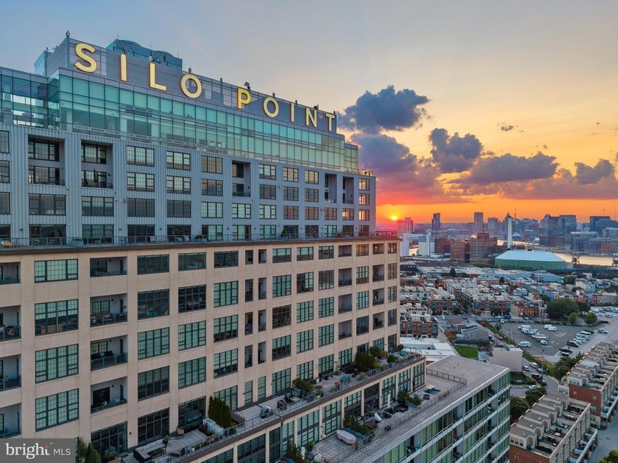 Experience unparalleled luxury living in this architecturally unique corner condominium located on the 18th floor of the iconic Silo Point. Enjoy panoramic and unobstructed water and city views from triple exposures in this highly sought-after two-bedroom, two-and-one-half-bath Tower residence. Offering over 2,200 square feet of refined, one-level living, this reimagined home captures dramatic skyline and harbor views from every angle. Masterfully redesigned by architect Mitchell Owen of MOD Group and executed to perfection by Greenleaf Construction, the residence underwent a full transformation in 2023; including all-new HVAC, plumbing, lighting, and top-of-the-line appliances. The result is a striking blend of industrial heritage and modern luxury, anchored by original concrete columns from the building’s historic grain elevator past. Walls of glass facing west, north, and east flood the space with natural light, framing breathtaking vistas across the city and water. A private east-facing balcony offers the perfect setting for a morning espresso or an evening wind-down. Inside, Carlisle heirloom white oak floors run throughout, setting the stage for rich, custom walnut built-ins that elevate both the kitchen and living areas. The chef’s kitchen is a centerpiece of the home—meticulously designed with oversized Caesarstone quartz countertops, custom soft-close walnut cabinetry, and a fully integrated appliance suite that includes a Sub-Zero refrigerator, Wolf induction cooktop with ceiling-mounted hood, Wolf E-series oven and speed oven, and a Miele dishwasher with automatic detergent dispenser. A beautifully integrated custom coffee station adds functionality and flair, making daily rituals feel indulgent and effortless. The serene primary suite features balcony access, a spacious walk-in closet with custom organization, and a spa-inspired en-suite bath adorned with Dornbracht and Toto fixtures, a freestanding Victoria & Albert Amiata soaking tub, and a quartz double vanity. The equally spacious guest bedroom includes its own en-suite bath, offering privacy and comfort for visitors. Additional features include a beautifully finished powder room, a full-size LG washer and dryer with additional storage, Lutron motorized blinds, and upgraded lighting throughout. Two deeded garage parking spaces convey. Residents at Silo Point enjoy a full-service lifestyle, including a 24-hour front desk concierge, on-site building management, a state-of-the-art fitness center with yoga studio and private treatment room, game room, boardroom, and the show-stopping 19th Floor Sky Lounge with panoramic views. Originally constructed as a 1920s grain elevator, Silo Point has been transformed into one of Baltimore’s most architecturally iconic residential communities—offering an unmatched blend of bold design, luxury amenities, and exceptional waterfront living.