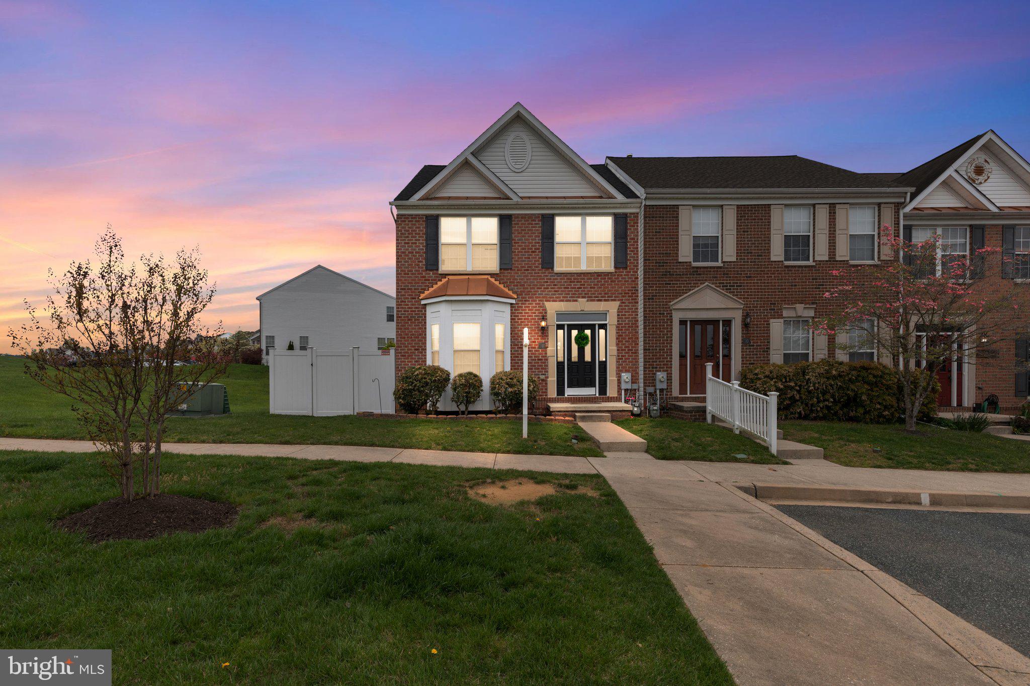Nestled in the sought-after Emerald Hills neighborhood, this spacious end unit brick-front townhome offers the perfect blend of comfort and style. Enjoy over 2800 square feet of finished living space. Step inside to discover hickory hardwood floors throughout the main level, complemented by neutral paint that sets the stage for any décor. The adorable drop zone inside the front foyer adds convenience to your daily routine. Entertain with ease in the spacious and open kitchen featuring a large island and stainless appliances. Connected to the kitchen is a family room with an abundance of natural light. Upstairs, retreat to the primary suite boasting two walk-in closets, a soaker tub, and stall shower. With two additional bedrooms, a second full bath, and convenient upstairs laundry you will have plenty of space. The lower level impresses with luxury vinyl planking flooring and a bonus bedroom complete with a full bathroom. The lower level walkout exits to a beautiful stamped concrete patio and private yard within the 6-foot vinyl fence. Enjoy convenience of the main level Trex deck that also leads to the lower-level patio, complete with built-in storage under the deck (2022). With a new roof (2023) and front and rear doors being installed next week, this home is ready to welcome you. Plus, take advantage of neighborhood amenities including a pool, tot lot, and community center, all conveniently located nearby.