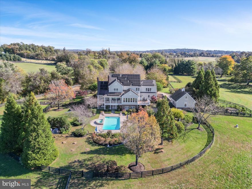 AMAZING VIEWS, POOL, AND 15-ACRE ESTATE IN UNBEATABLE LOCATION. Welcome to a rare Loudoun County treasure and Weatherburne-built estate home that blends timeless craftsmanship with modern sustainability. This property backs to conservation land, protecting the views from future development. Arrive through stone columns, pavered entrance and a tree-lined pea gravel drive to a circular pavered courtyard, where equestrian amenities and open paddocks set the stage for Virginia Countryside Living. Inviting brick laid wrap front porch welcome family and friends.  Hardi plank/brick exterior. Inside, oak hardwood floors entire main and second levels, coffered ceilings, and four fireplaces create warmth and elegance. New Taj Mahal quartzite counters in the kitchen. The amazing kitchen flows into a sunroom dining area and covered porch, perfect for entertaining against the backdrop of mountain sunsets. Enjoy the Surround sound in the basement, main floor, covered porches, near pool, and in master bedroom/bathroom. Intimate conservancy room with coffered ceiling/ with both gas and or wood burning fireplace.  Family room features coffered ceiling, stone wood burning fireplace completed with built in cabinets/bookcases on either side. Primary bedroom suite offers a private gas fireplace and spa-like bath. Three more bedrooms and two full baths complete this level. The upper level above has two more bedrooms and a full bath. The lower-level retreat features a stone wood or gas fireplace, exercise and game rooms, bedroom, two full baths and walkout access to the pool. Outdoors heated pool and spa are framed by gardens, mature trees, and a cascading waterfall into a fishpond.  Fenced riding area, multiple paddocks with waterers and run in buildings for the equestrian world. Enclosed garden area. Separate detached two-car garage with staircase to loft. With a metal roof, seller-owned solar panels Sept 2023, geothermal heating/cooling 2016, whole-house propane generator December 2021, new windows 2020, this estate is as efficient as it is beautiful. Utility bills are next to nothing.  Propane leased tank for cooking, fireplaces and pool. No HOA, land use designation, and neighboring conservation easement ensure lasting privacy and freedom. Located ten minutes to Leesburg and the Toll Road, this property is more than a home— it’s a lifestyle of elegance, sustainability, and countryside serenity.