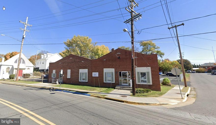 Prime Commercial Property in Berryville, VA - This well-maintained commercial property, located at the high-traffic intersection of N. Buckmarsh Street and Academy Street, offers great visibility and accessibility in the heart of Berryville. Zoned for commercial use, the site is improved by a 2,794± SF building and a three-bay garage, currently leased to established tenants including the Virginia Department of Health and Annabelle Beauty Salon. The property features paved off-street parking with 23 spaces, five of which are leased to Ridgeway's Autobody, ensuring additional income potential.