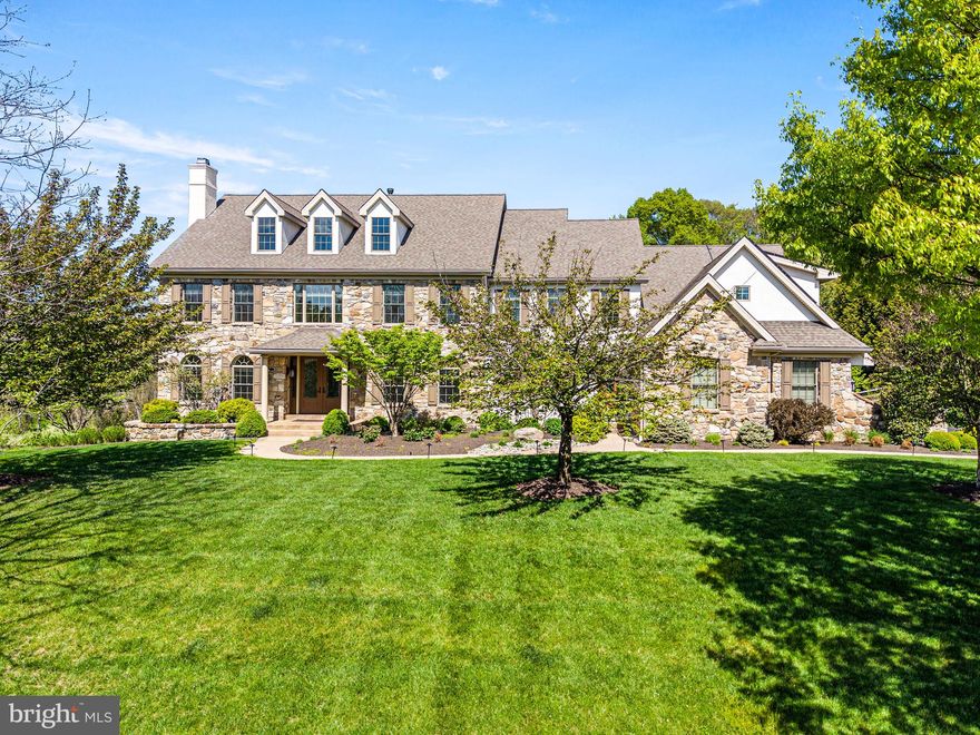 Welcome to this spectacular, impeccably maintained home situated on a premium lot in a most desirable neighborhood. Impressive curb appeal with professional landscaping and lighted walkway sets the tone for what awaits inside. Step through the front door and experience a refined, elegant interior filled with natural light streaming through expansive windows, highlighting rich hardwood floors and exquisite millwork. The sophisticated living room offers an inviting space to gather, complete with a gas fireplace featuring a stone surround and handsome woodwork. The generously sized formal dining room is ideal for both intimate dinners and larger celebrations and is complemented by a convenient butler’s pantry and wine refrigerator for seamless entertaining. The stunning, designer kitchen is truly a showpiece, featuring floor to ceiling walnut cabinetry, illuminated open shelving, and a striking glass wine closet with translucent quartzite. Crisp white cabinetry and quartz countertops add contrast, while the oversized island comfortably seats five. Premium appliances include separate Sub-Zero refrigerator and freezer units, two Bosch dishwashers, a Wolf double oven, a Wolf six burner cooktop with griddle, and a Wolf built in microwave. The bright breakfast room overlooks the picturesque backyard and opens to a spacious low maintenance deck, perfect for outdoor dining. The private backyard oasis showcases lush landscaping with blooming trees and shrubs, along with a heated, salt water pool featuring a waterfall, lighting, and expansive flagstone patio and decking. Adjacent to the kitchen, the large family room features a wood burning fireplace with an impressive surround and a wall of windows that brings the outdoors in. The main level also includes a spacious office with custom built ins, a light-filled sunroom, a mudroom with built-in cubbies, and two half baths. Upstairs, the primary suite offers a private retreat with sitting room, gas fireplace, and built in cabinetry, along with two large custom closets and a luxurious bath with dual vanities and soaking tub. Two guest bedrooms feature en-suite baths, while two additional bedrooms share a Jack and Jill bath. A large laundry room with abundant storage completes this level. The finished walk-out lower level is equally impressive, boasting a large recreation/game space with gas fireplace and a granite bar equipped with refrigerator, dishwasher, and microwave. The media room is designed for entertainment with projector, screen, surround sound, and leather power recliner seating. This level also includes a guest room, two full baths, a gym area, and generous storage space. Additional features include a whole house generator, solar panels, two electric vehicle chargers, water filtration system, irrigation system, and landscape lighting. Situated in the highly sought-after Unionville-Chadds Ford School District, minutes from West Chester Borough and Longwood Gardens, with easy access to major routes, shopping, and dining. Truly an extraordinary, move-in ready home just waiting for its lucky new owners!